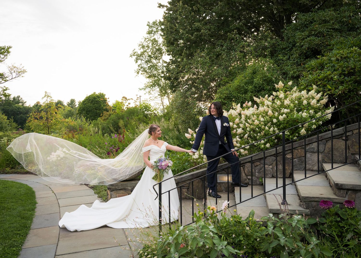 Romantic wedding couple poses in a spring garden with hanging white decorative spheres.