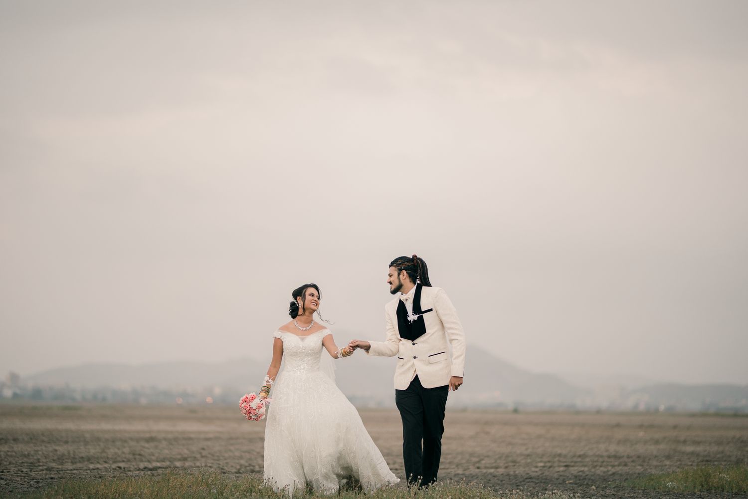 Romantic wedding portraits in a misty field with dramatic cloudy skies, captured by a professional wedding photographer in Mumbai.