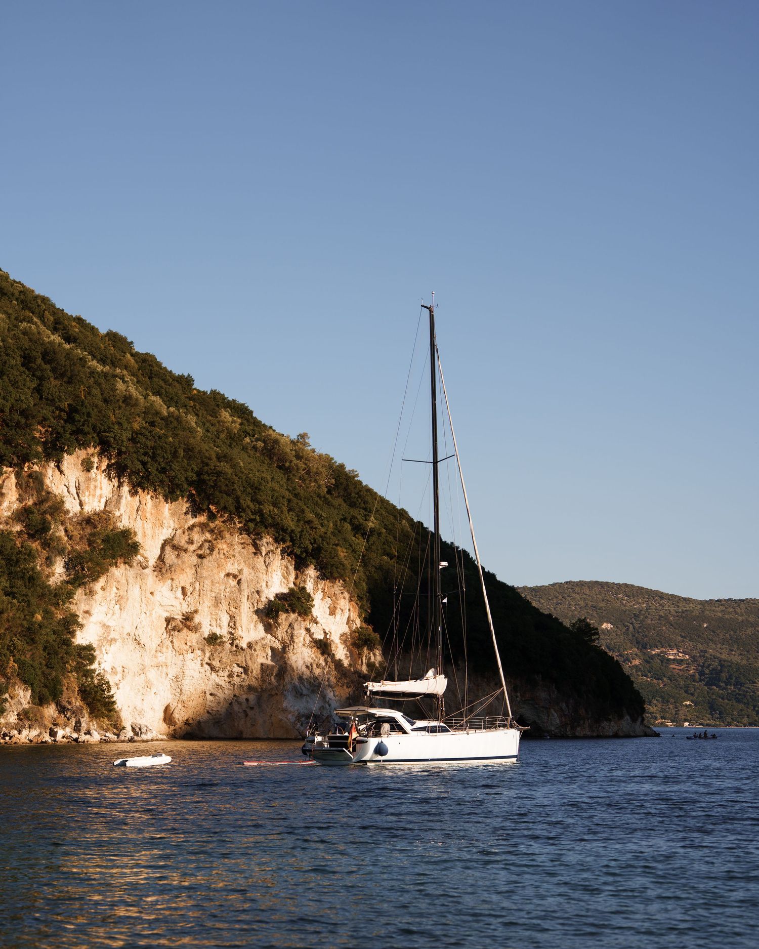 Panoramic view of rocky coastal cliffs and turquoise waters along a Mediterranean shoreline on a sunny day.