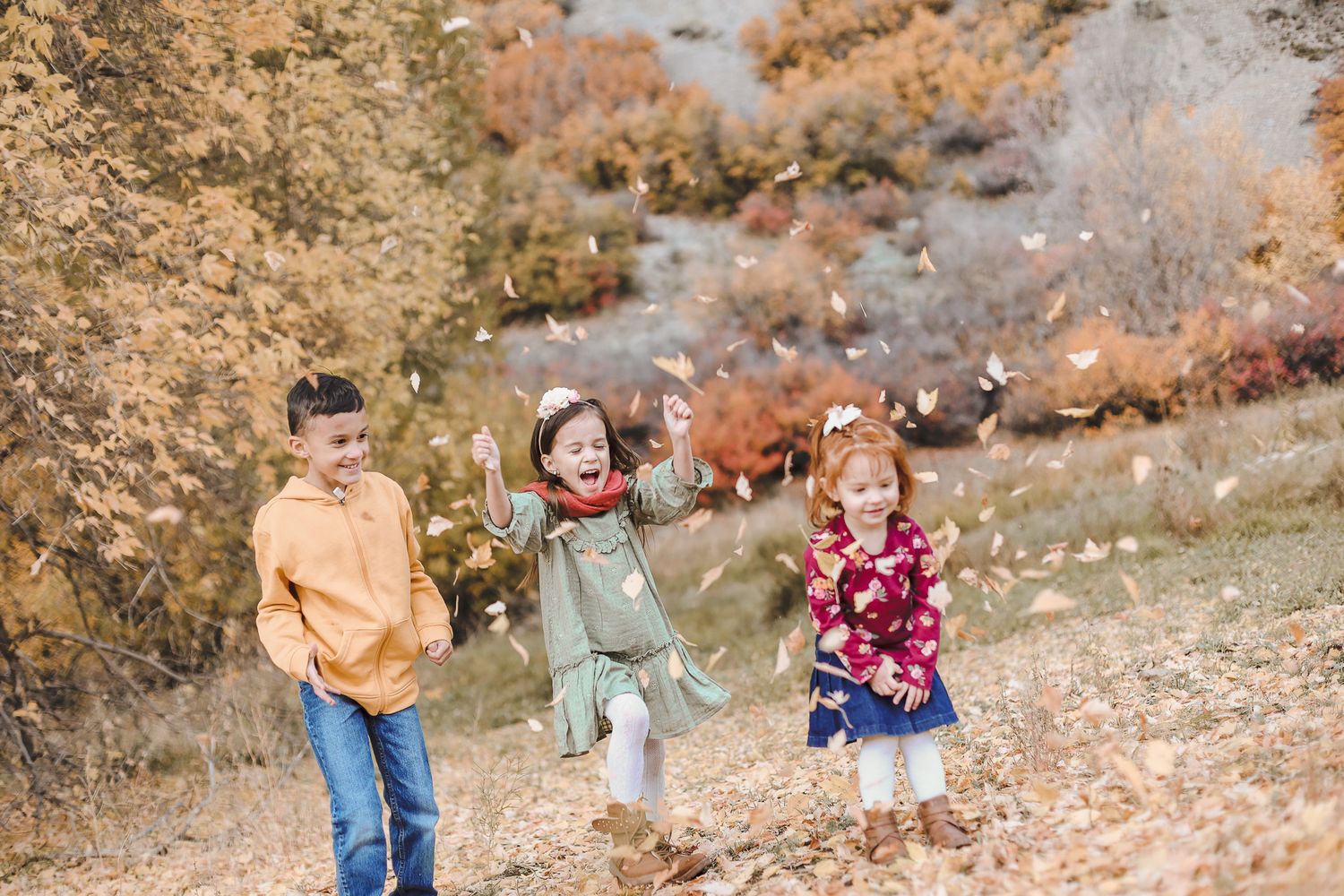 Family members walking and playing together in colorful autumn leaves and scattered white buckets on a fall afternoon.