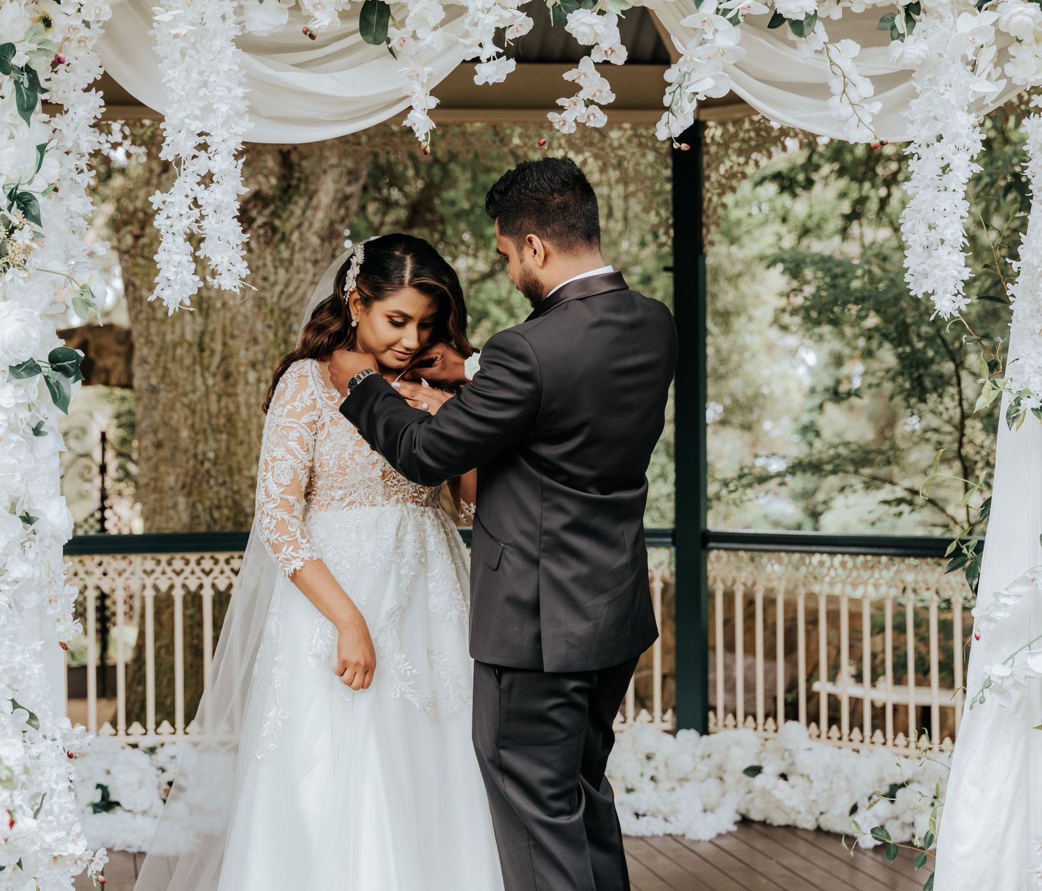 A romantic garden wedding scene with white floral decor and elegant draping creating an intimate atmosphere.