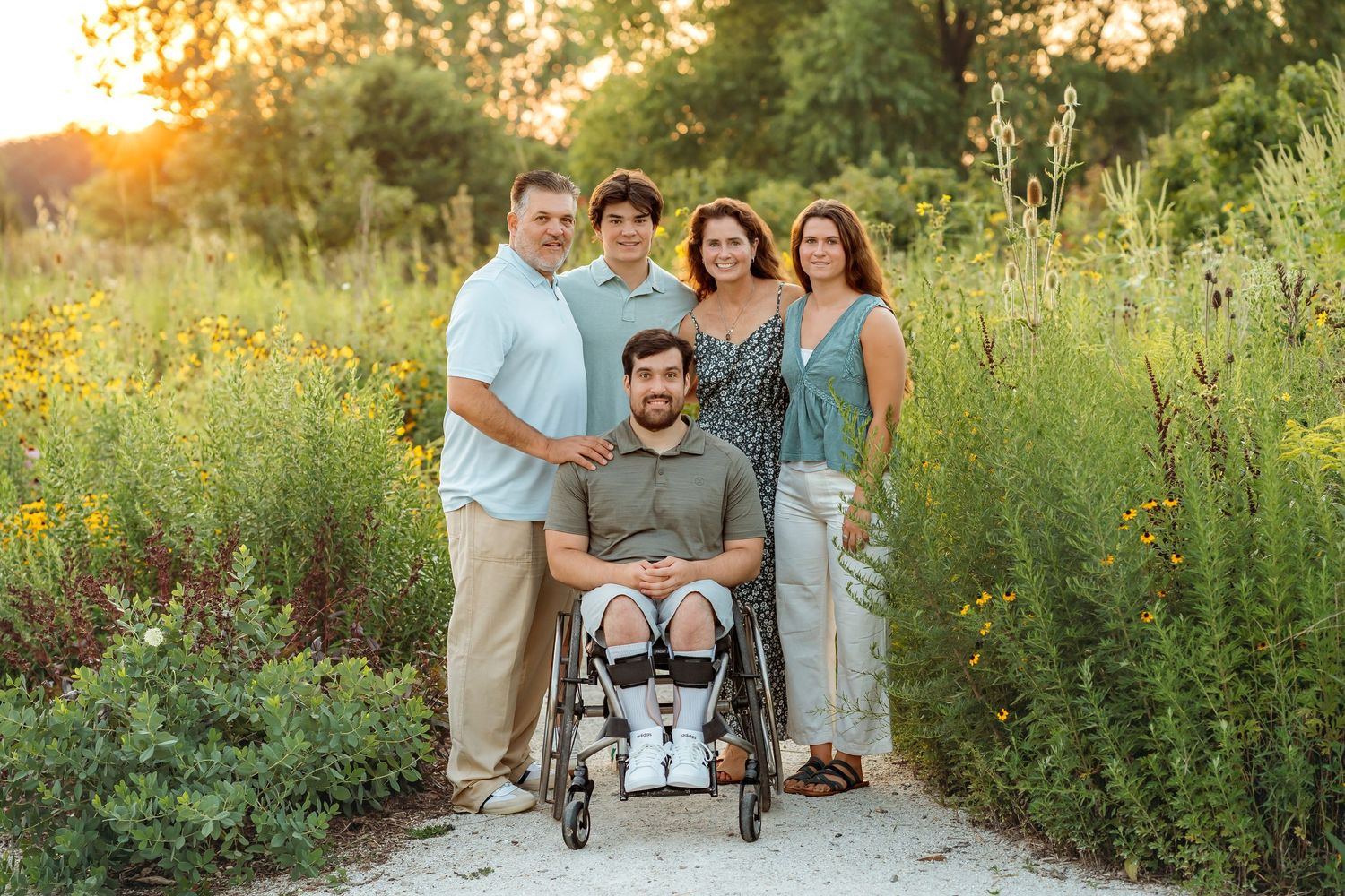Family portrait session in a golden wildflower meadow during sunset with soft natural lighting.