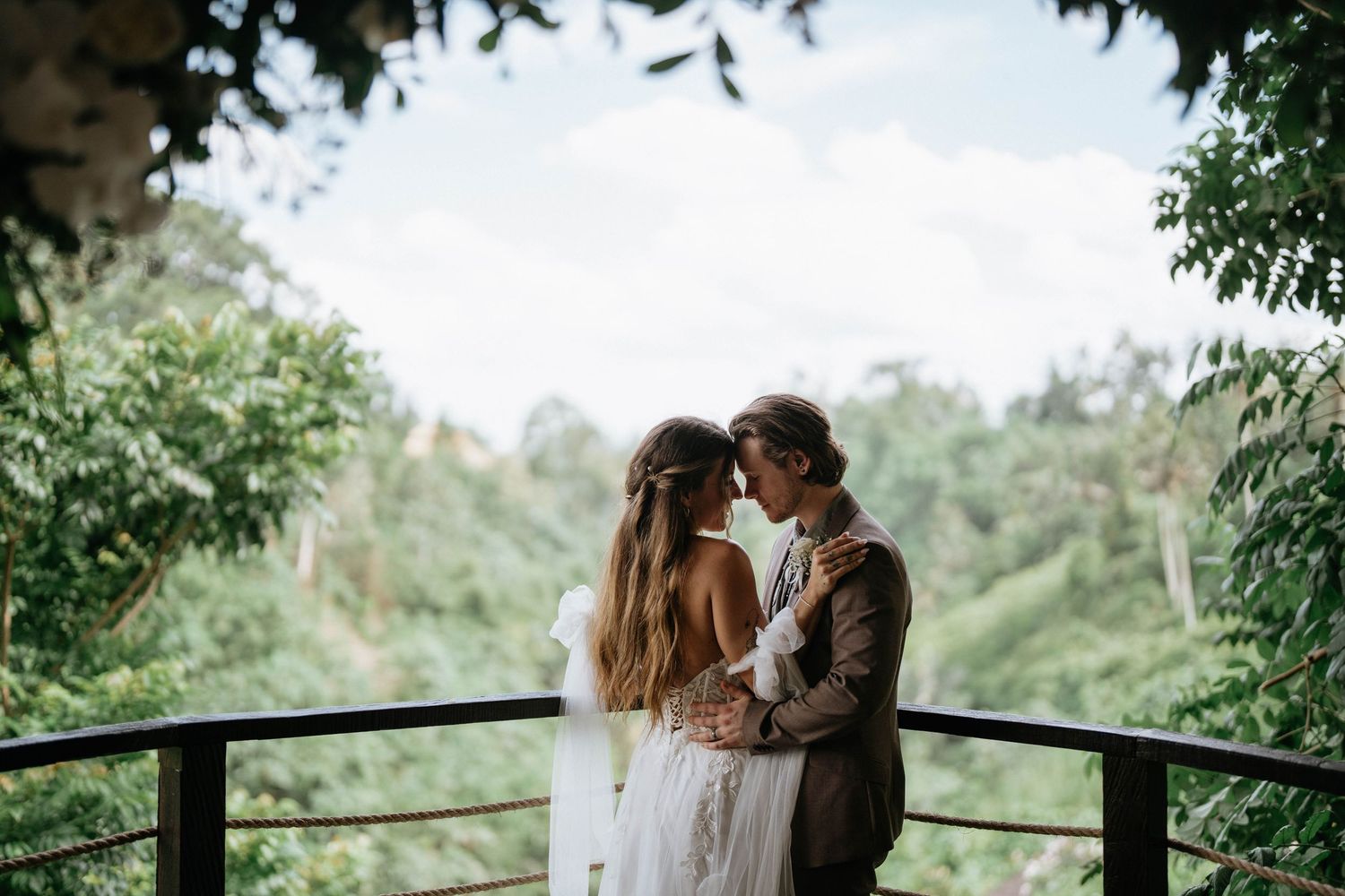 A romantic moment captured on a viewing deck overlooking a lush tropical valley.