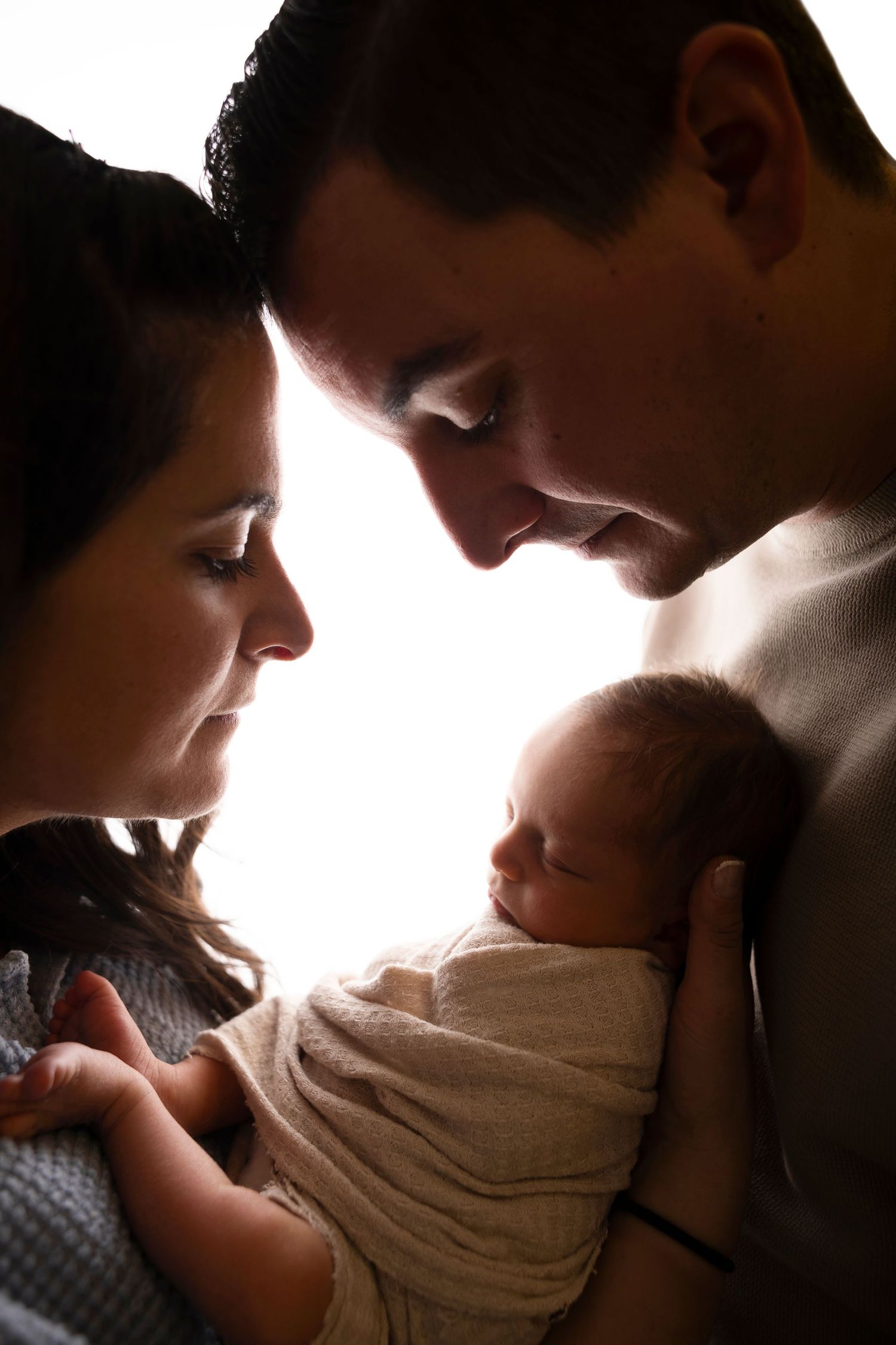 Silhouetted figures share intimate moments with a baby in a series of tender backlit photographs.