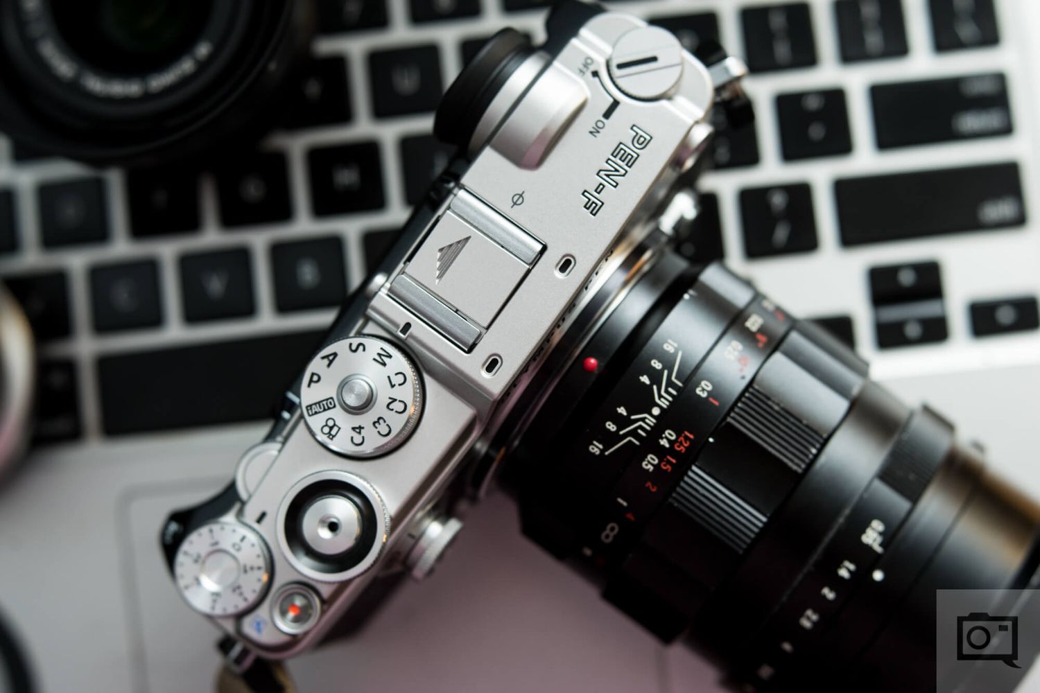 Several mirrorless digital cameras and lenses arranged on a black and white keyboard surface.