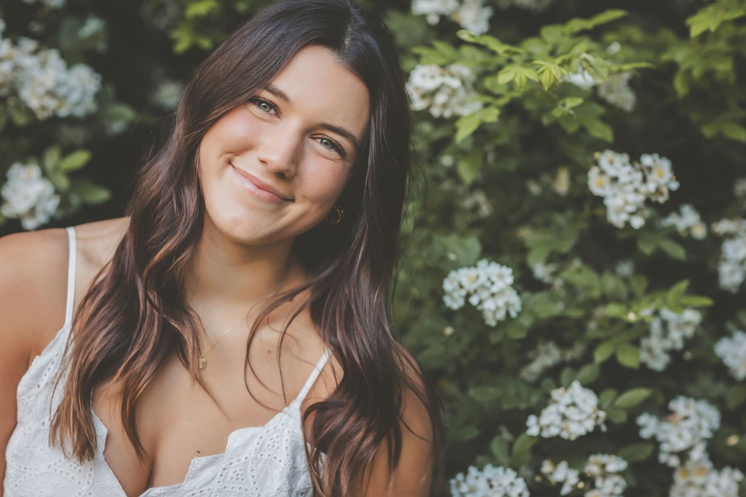 Spring portrait with white flowers and greenery in natural outdoor setting.