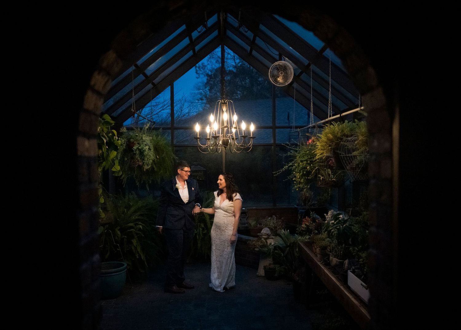 Newlyweds share an intimate moment outdoors with autumn foliage and rustic architecture in background.