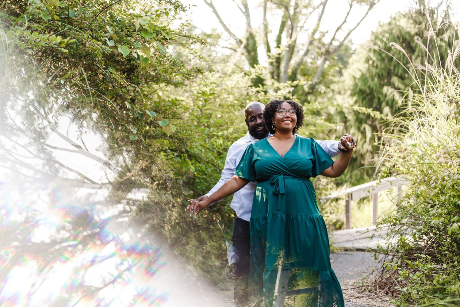 People walking together on a scenic sunlit forest trail wearing coordinated teal-colored outfits.