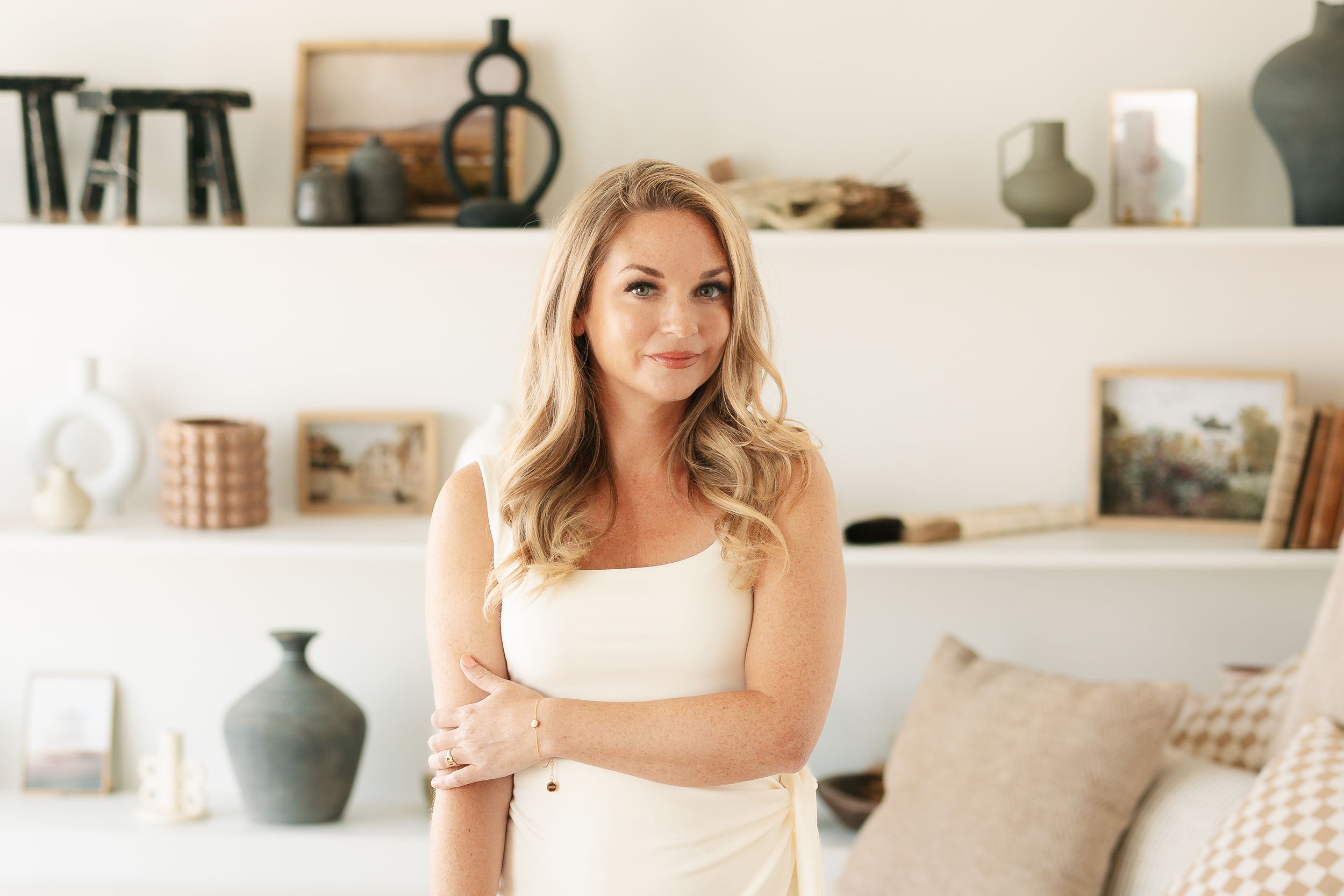 Elegant portrait in a minimalist room with decorative pottery displayed on shelves.