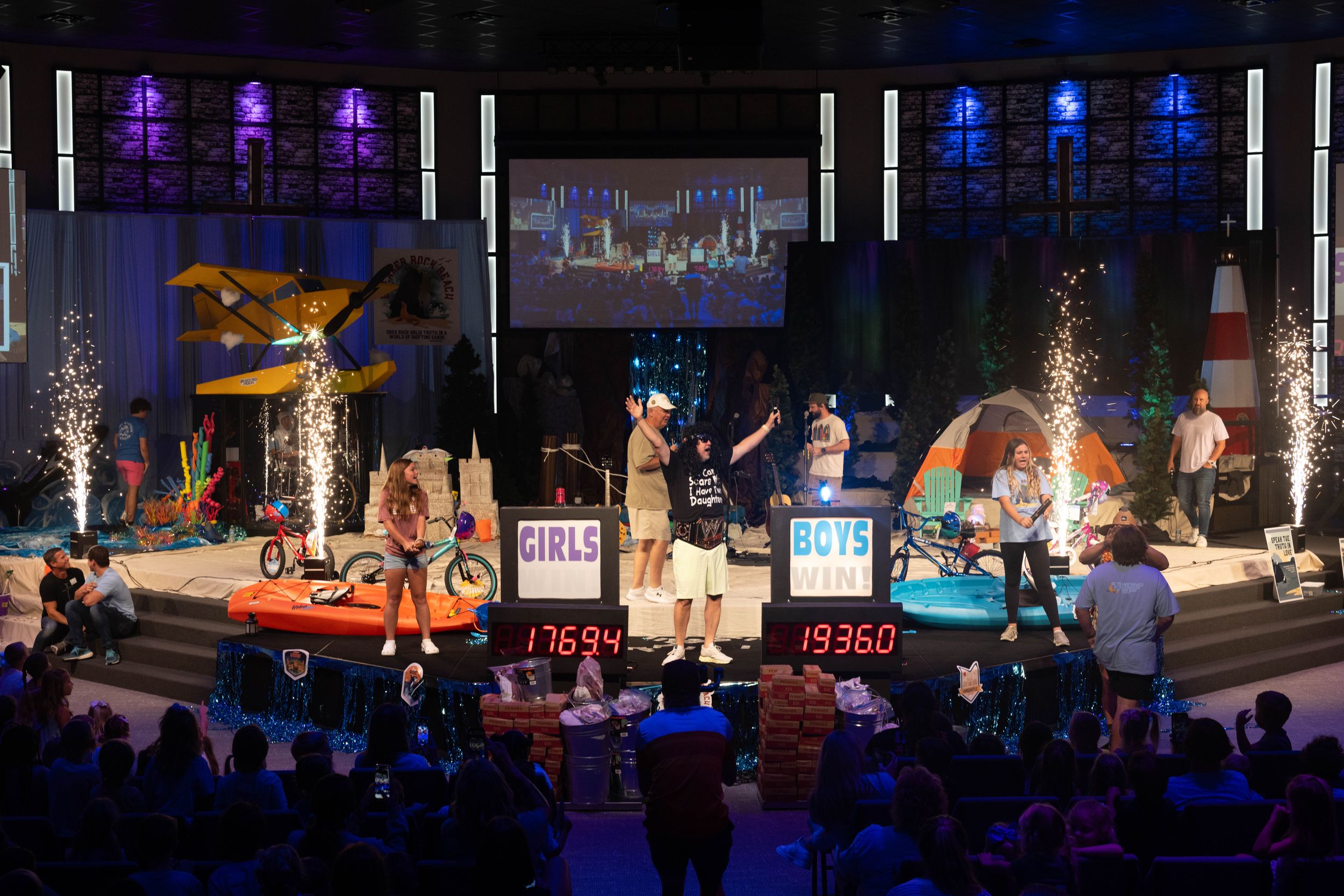 Stage performance with colorful lighting and special effects in front of a seated audience.