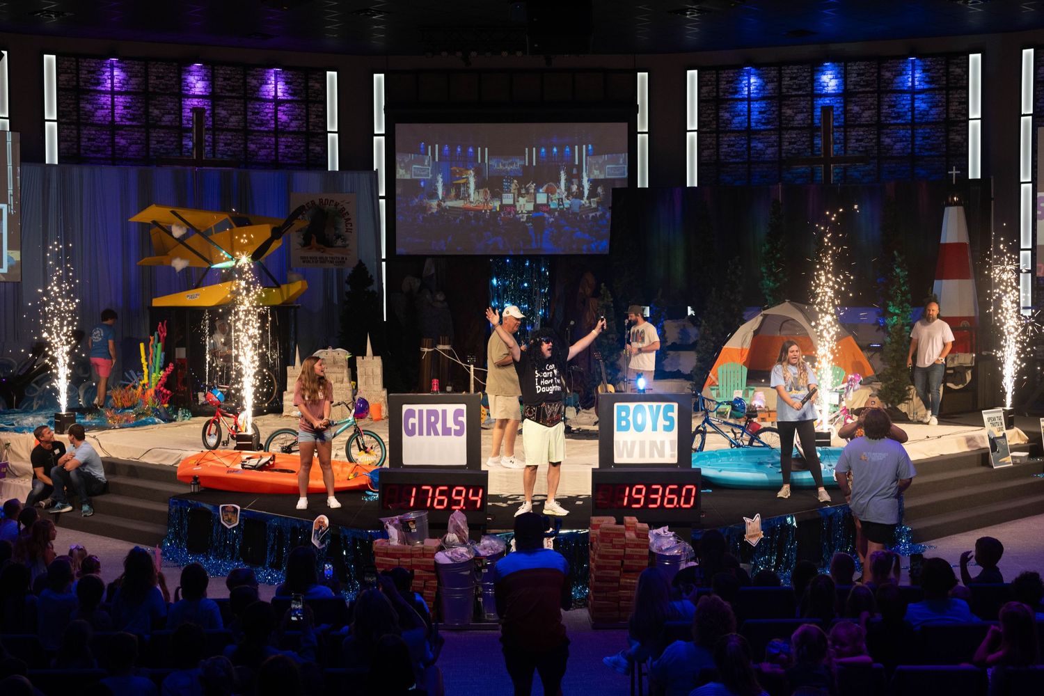 Stage performance with colorful lighting and special effects in front of a seated audience.