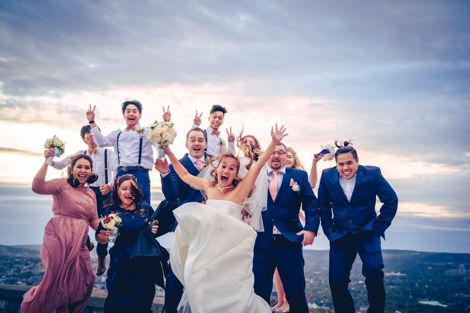 Happy bride shouting with bridesmaids and groomsmen on top of Signal Hill in St. John’s.