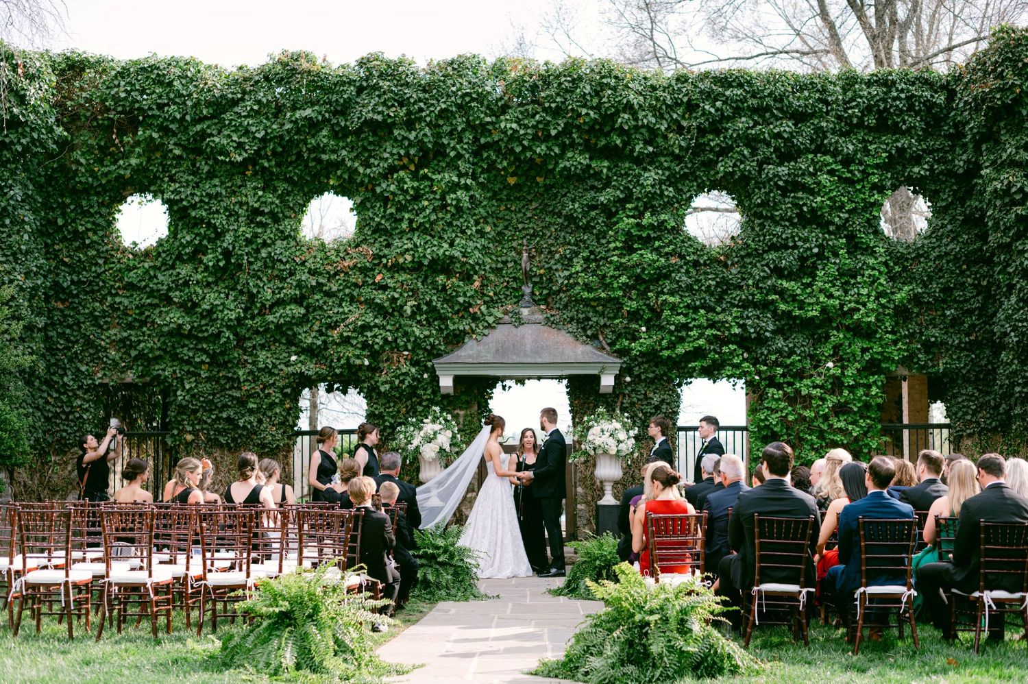 Goodstone Inn Wedding ceremony setup with ivy-covered wall and white floral arrangements in an outdoor garden.
