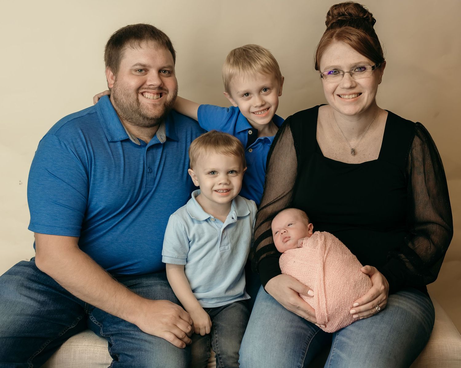 A studio portrait of a family group against a neutral background.