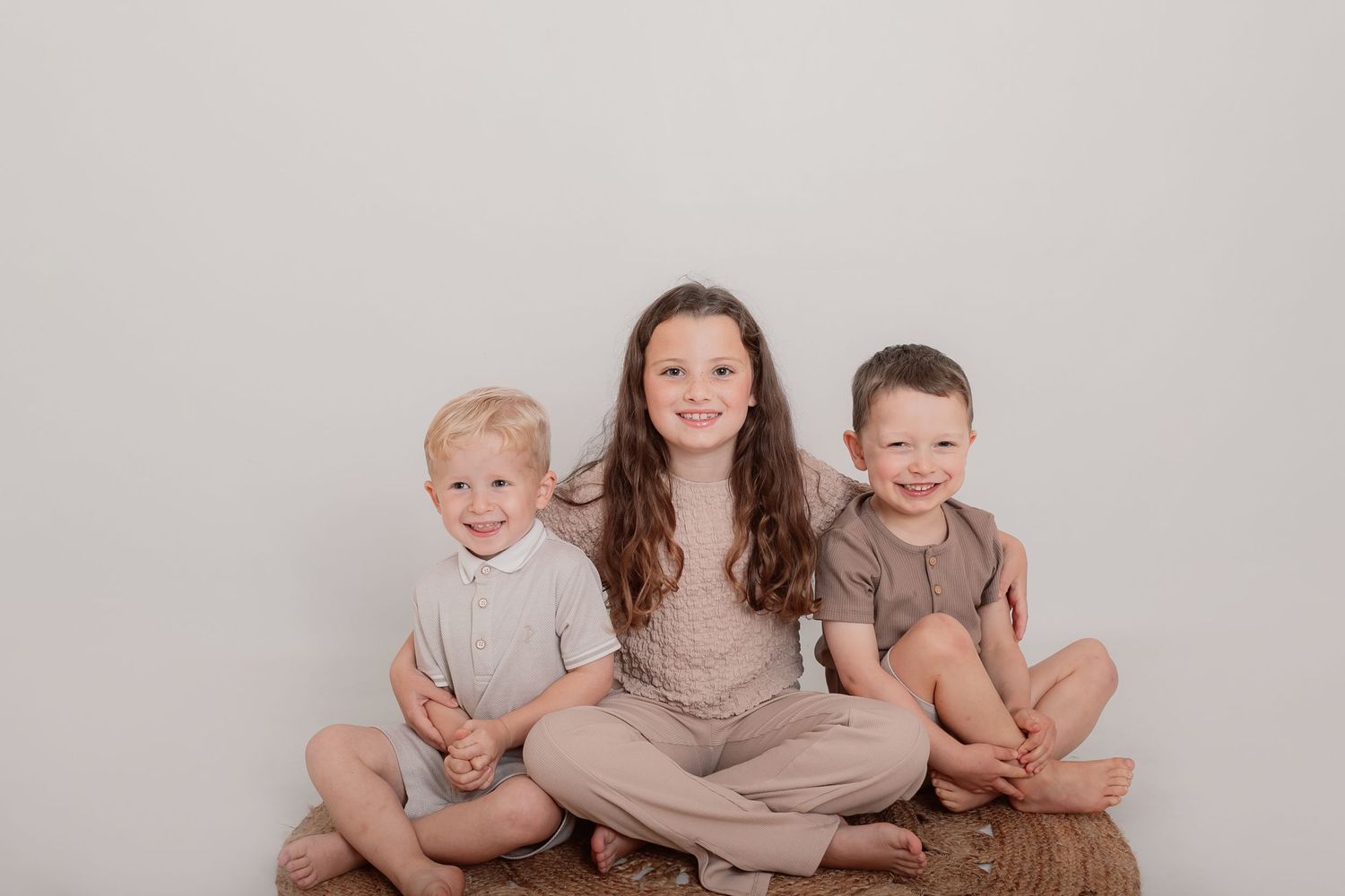 Family members sitting together in coordinated beige and brown outfits for studio portrait. Photographer. Hull. East Yorkshire. Photography