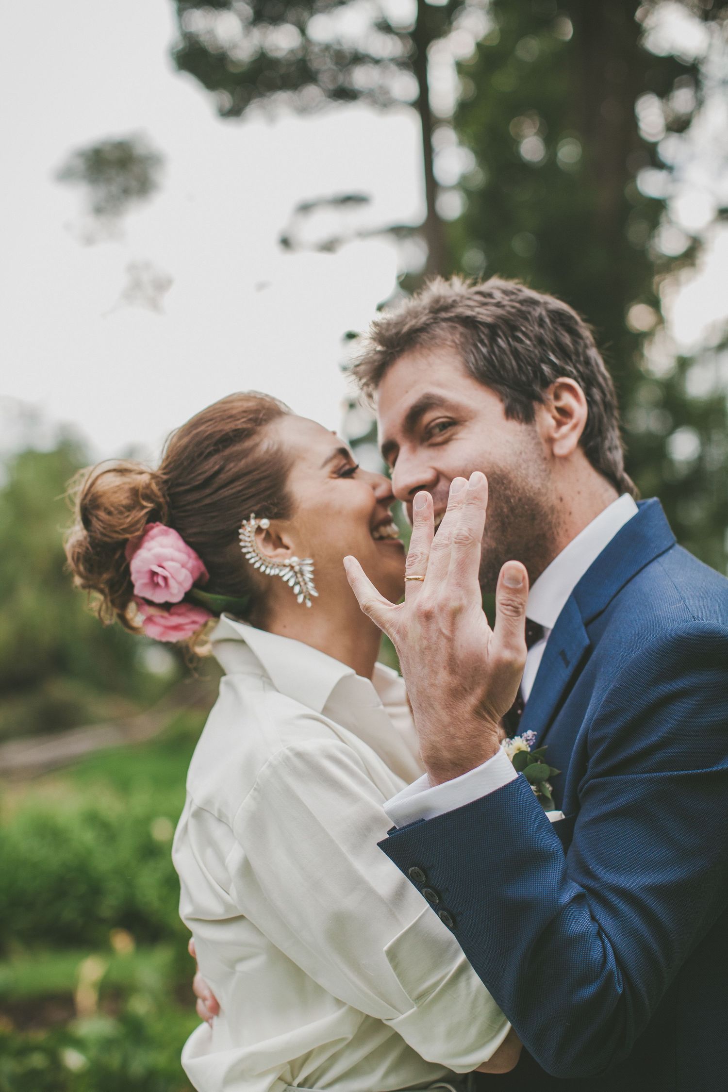 A romantic wedding moment captured in a natural outdoor setting with soft lighting and greenery in the background.