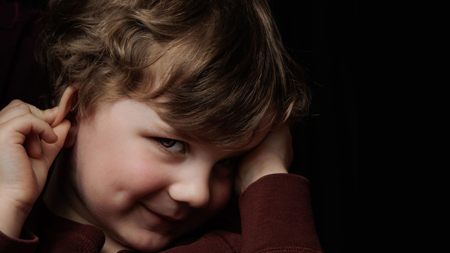 Close up of toddler on dark back drop looking at camera