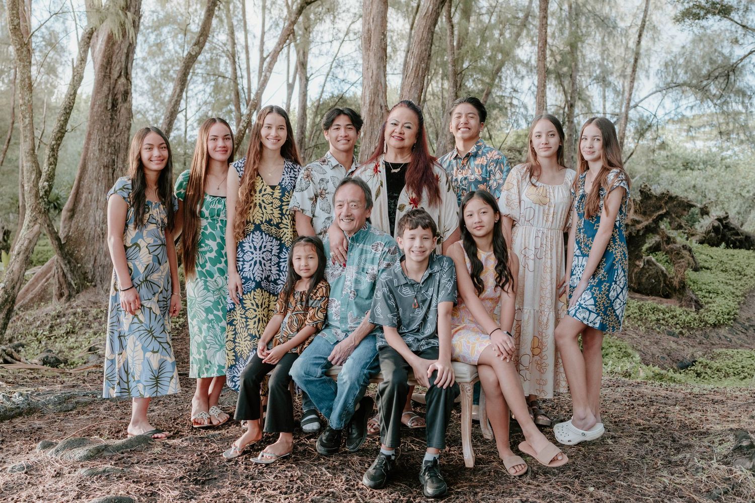 A group poses together in casual floral dresses among eucalyptus trees in a forest setting.