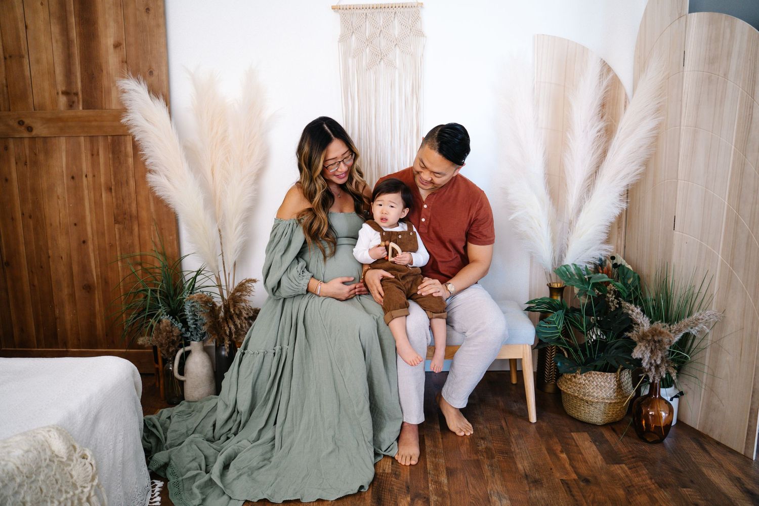 A family moment with a baby surrounded by decorative pampas grass and wooden accents.