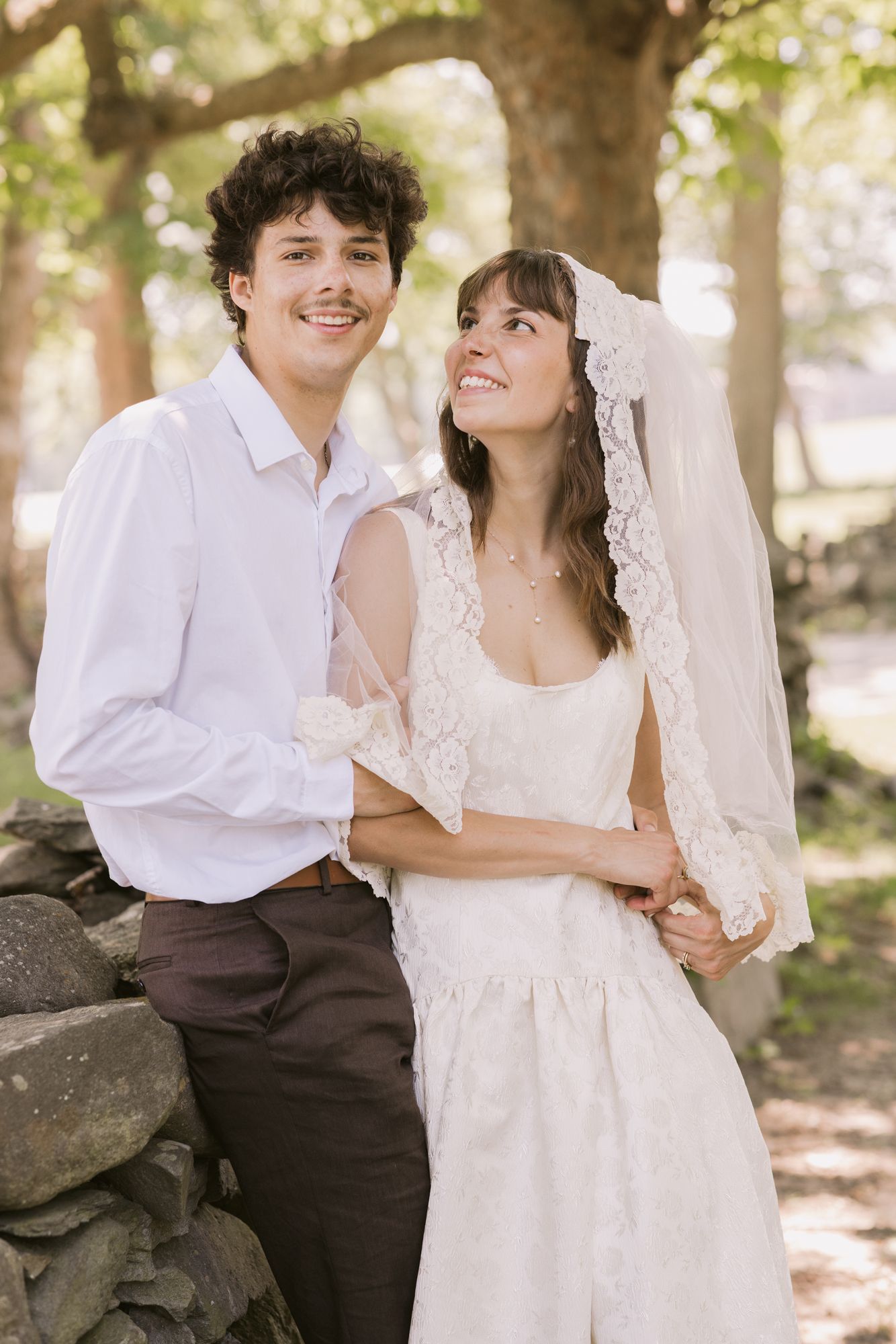 A happy bride looks lovingly at groom with a stone wall in background on their wedding day. Small wedding photographer Newport County.