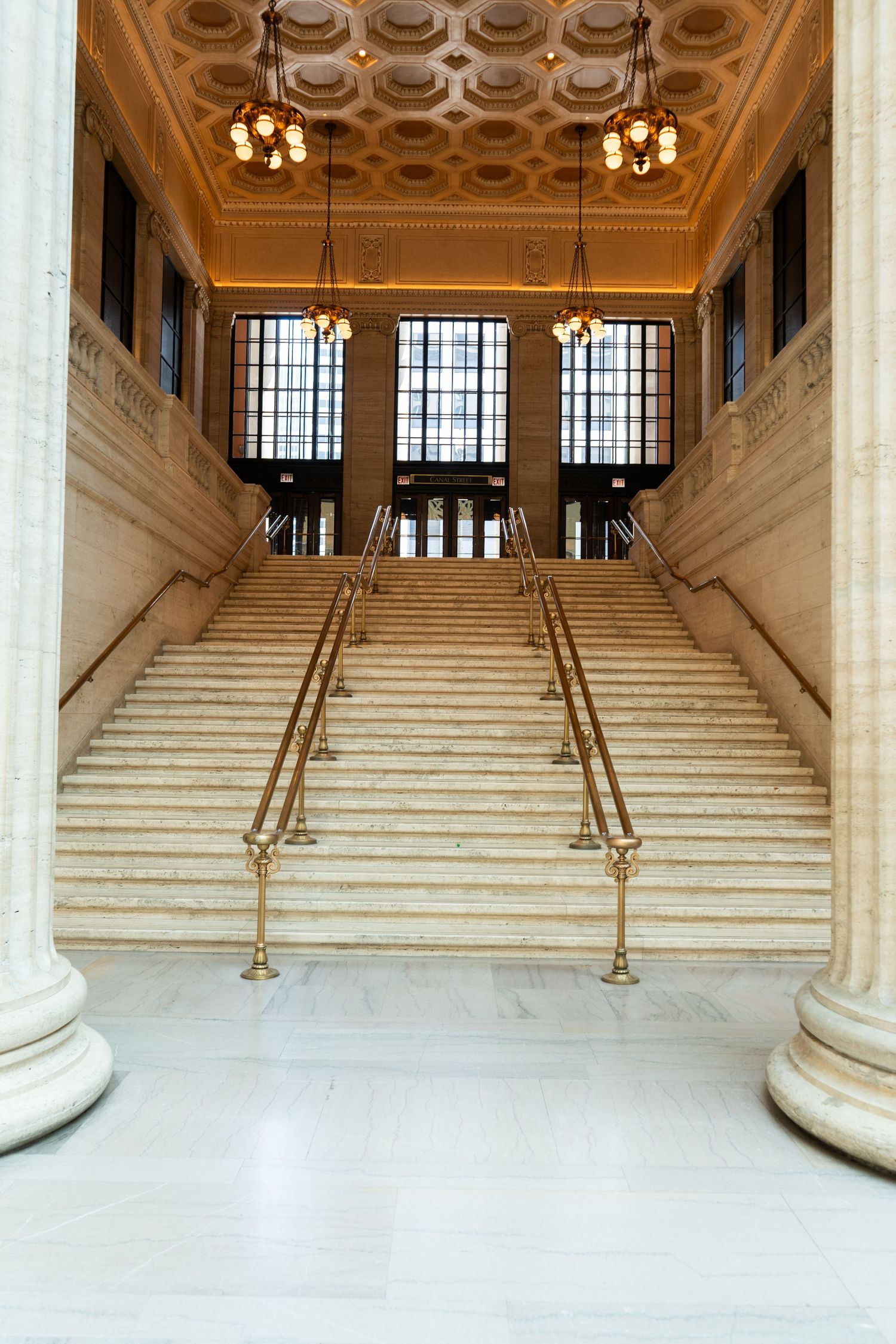 Elegant white marble staircase with ornate brass railings and decorative ceiling in a grand historic building interior | Sydney Allen Photo