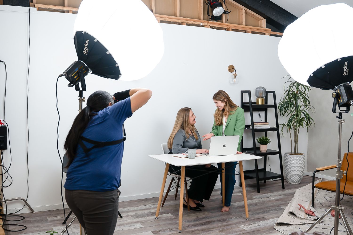 female brand photographer taking photo of 2 women business owners talking and working at desk on laptop in Bellevue, WA studio