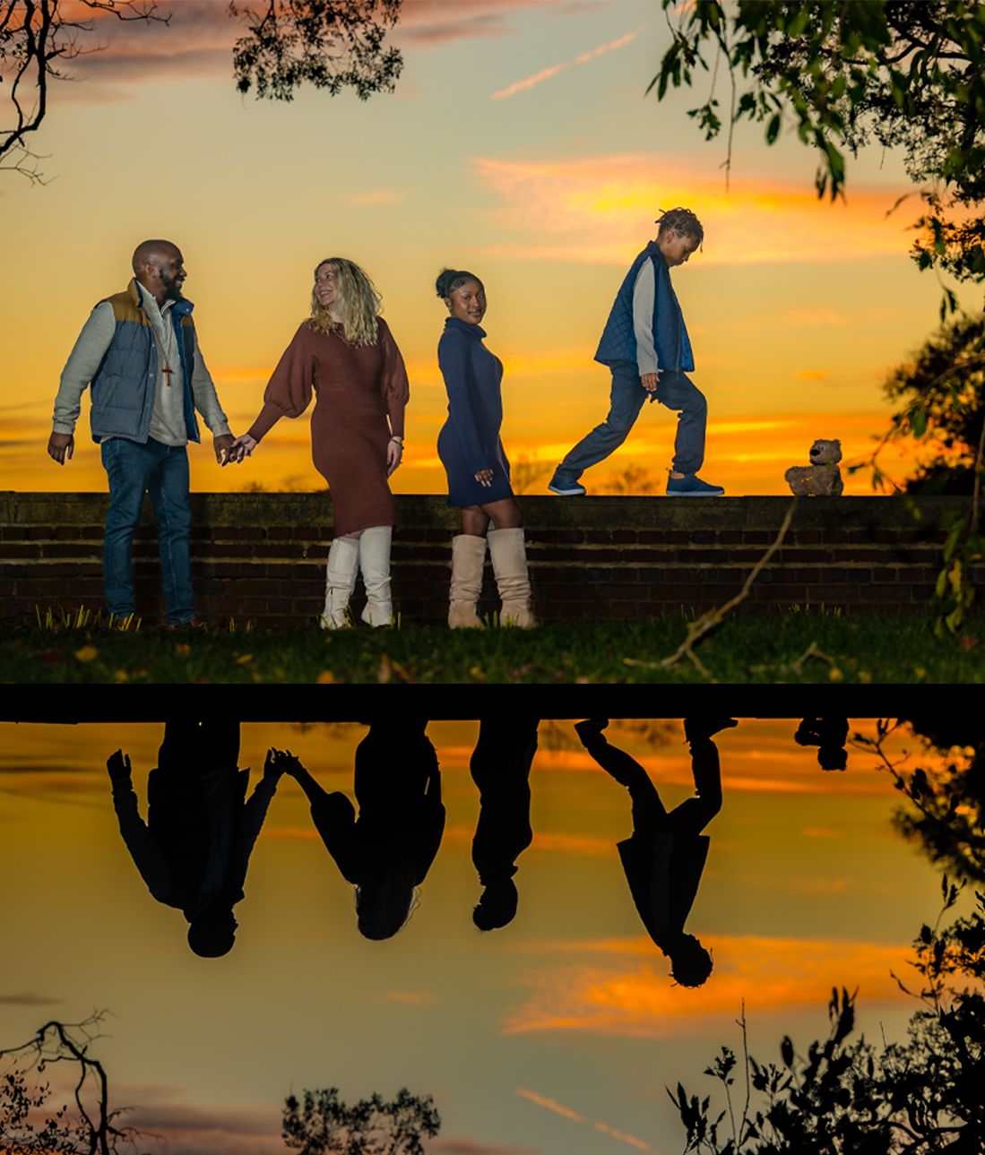 Four people holding hands at sunset reflected in water, silhouetted against vibrant orange sky.