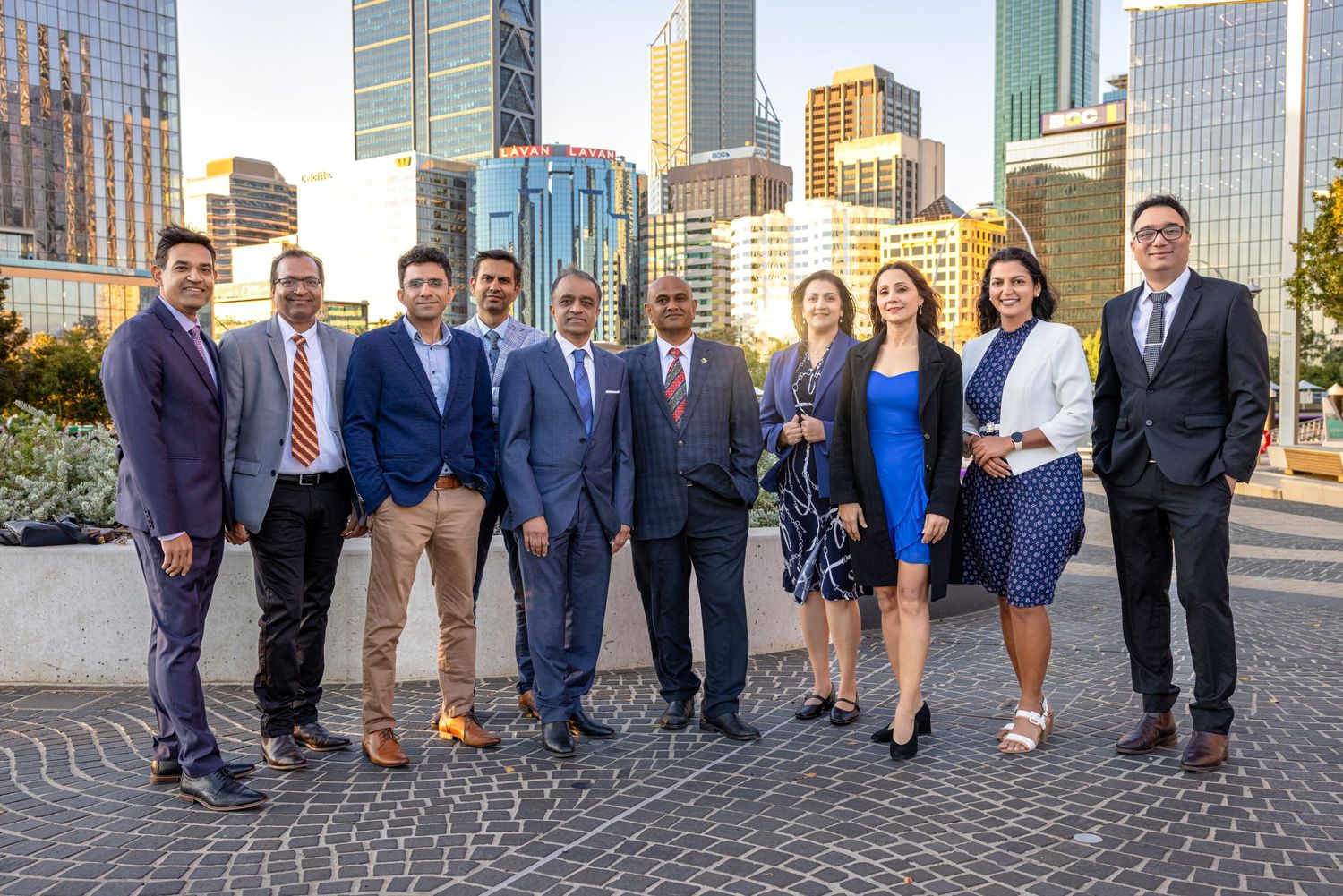Business professionals in formal attire standing together outdoors near modern office buildings in an urban setting.