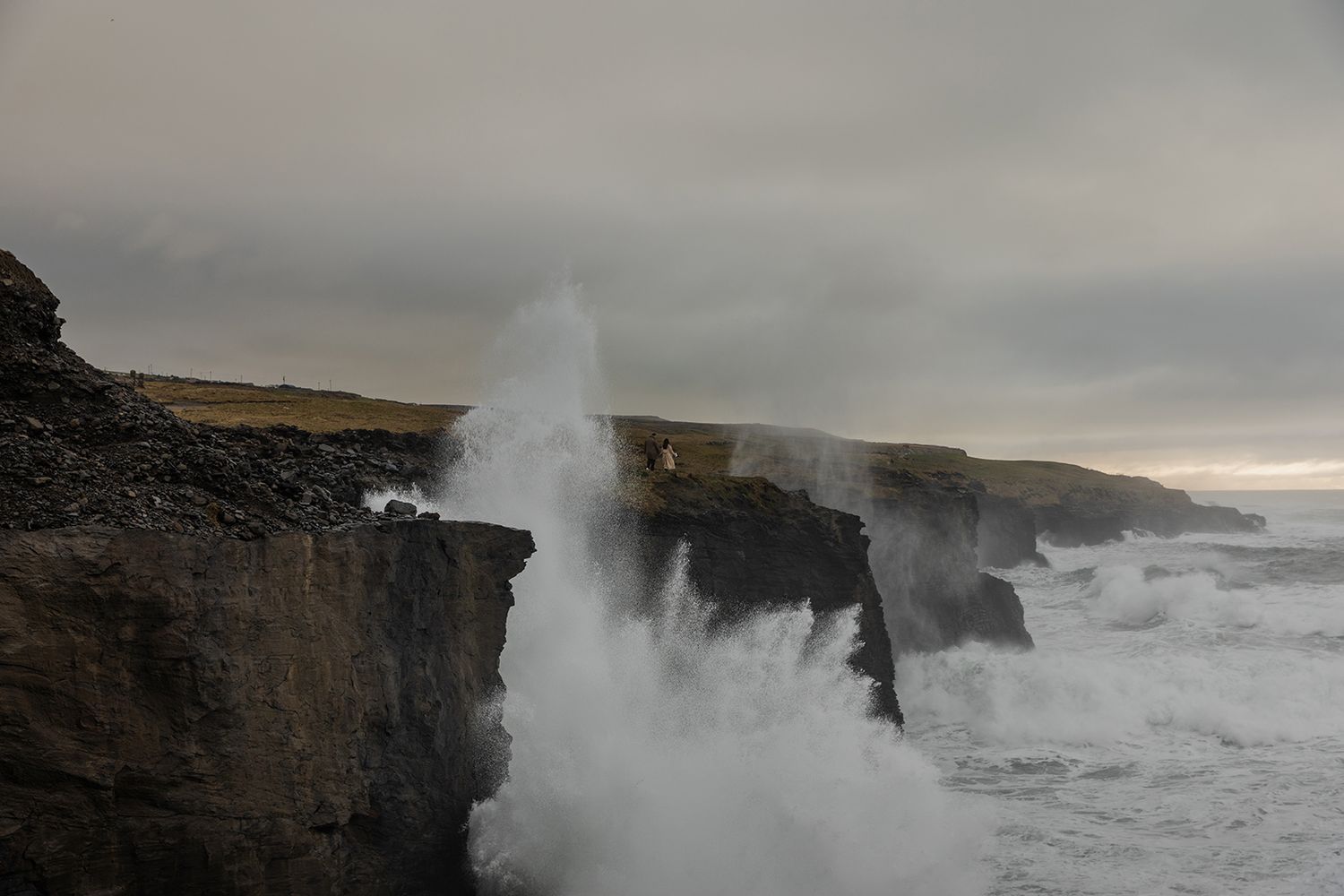 Dramatic sunset engagement session on Doolin Cliff Walk with stormy skies and crashing Atlantic waves at Cliffs of Moher