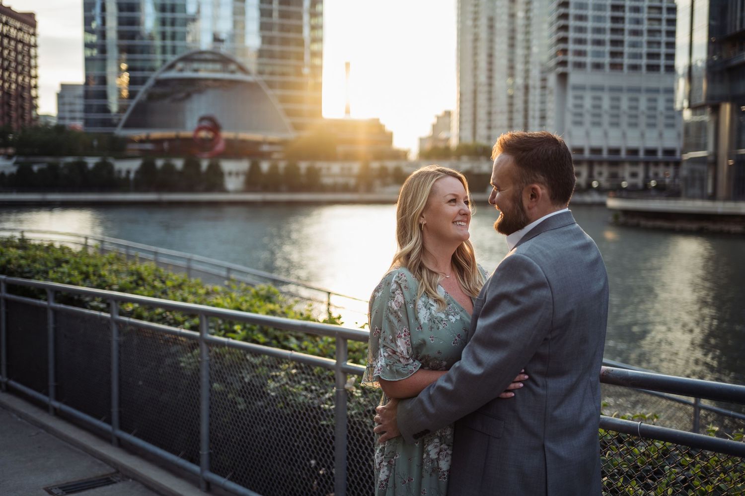 Couple embracing on Chicago Riverwalk Proposal at golden hour with city skyline in Chicago background.