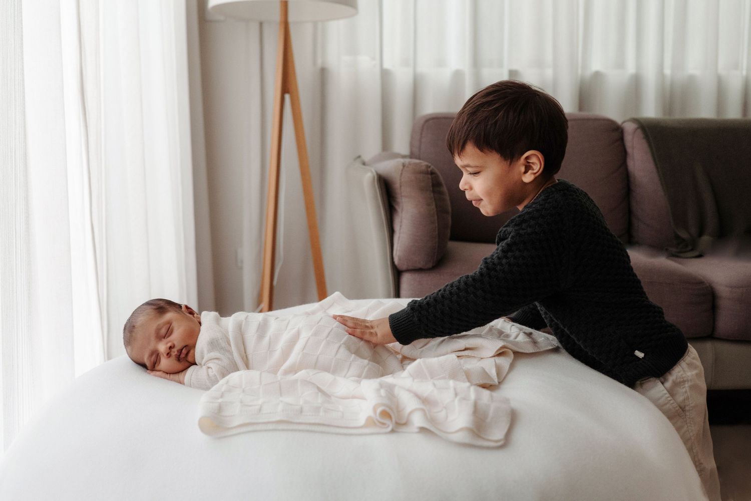 Toddler meeting newborn sibling during in-home newborn photography session