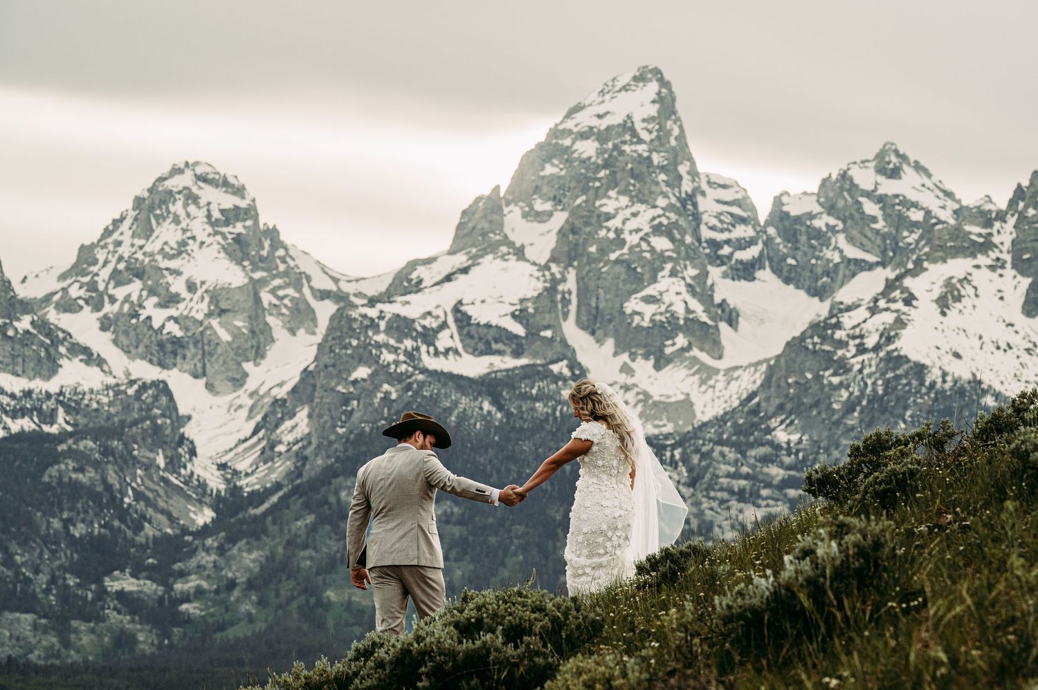 Couple embracing in wedding attire with the stunning Grand Teton mountain range in the background.