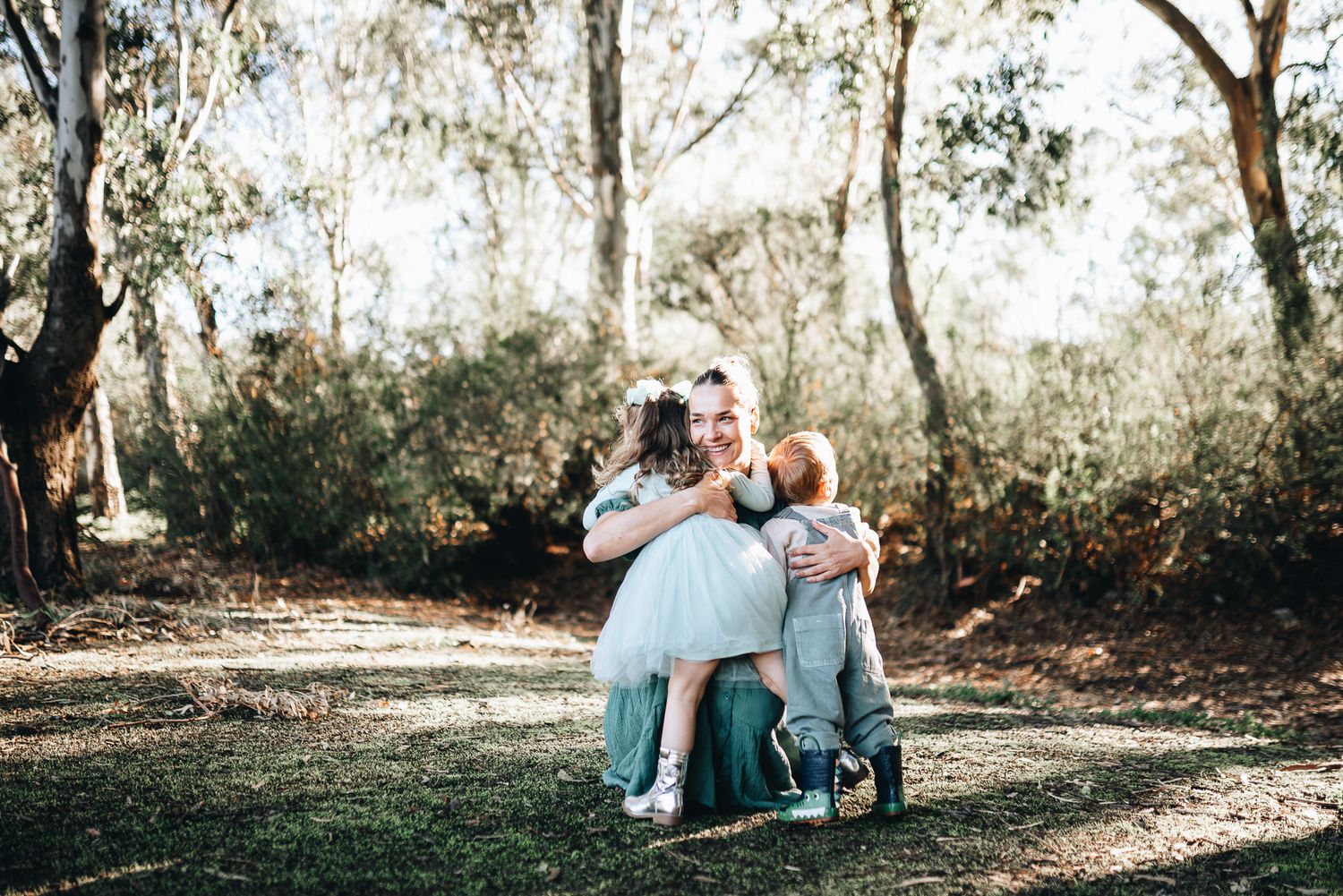 A series of outdoor family photos showing tender moments between parents and child in a sunlit wooded setting.