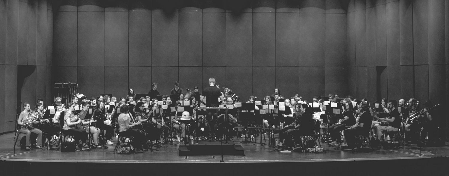 Black and white photo of a full symphony orchestra performing on stage in a concert hall.