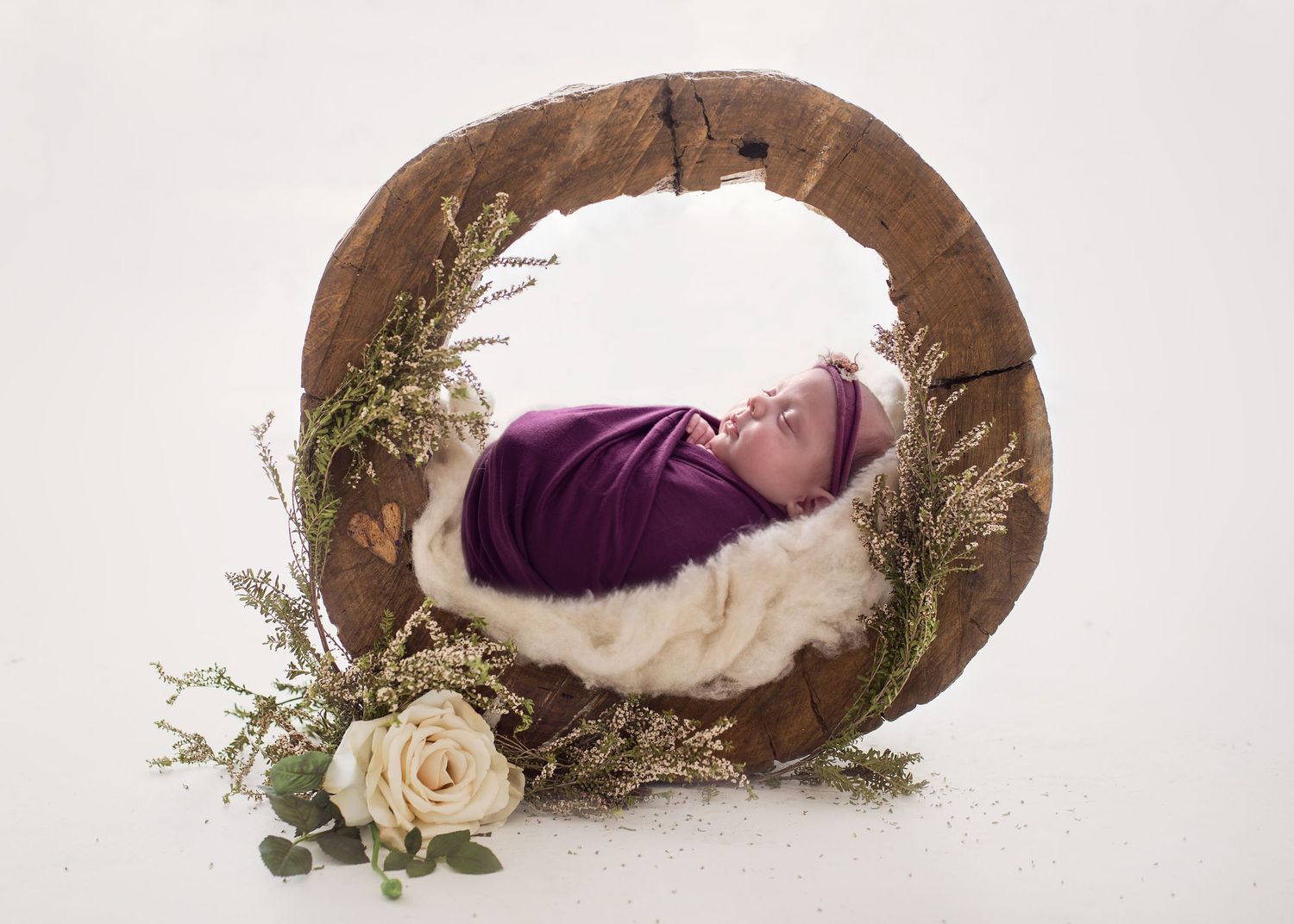 newborn baby girl posed inside a log with flowers around, everything is taken care of your your newborn photography session