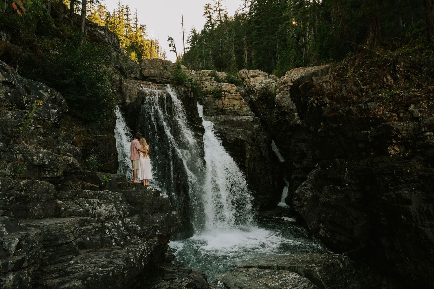 Couple adventure photoshoot session at Myra Falls on Vancouver island taken by professional photographer of couple looking at waterfall