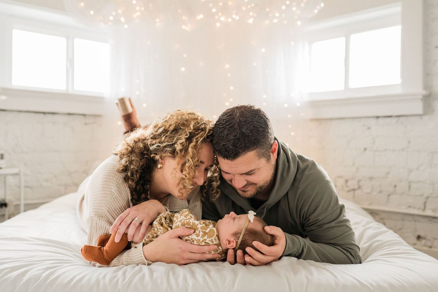 Couple sharing tender moments together in a bright white room with exposed brick walls.
