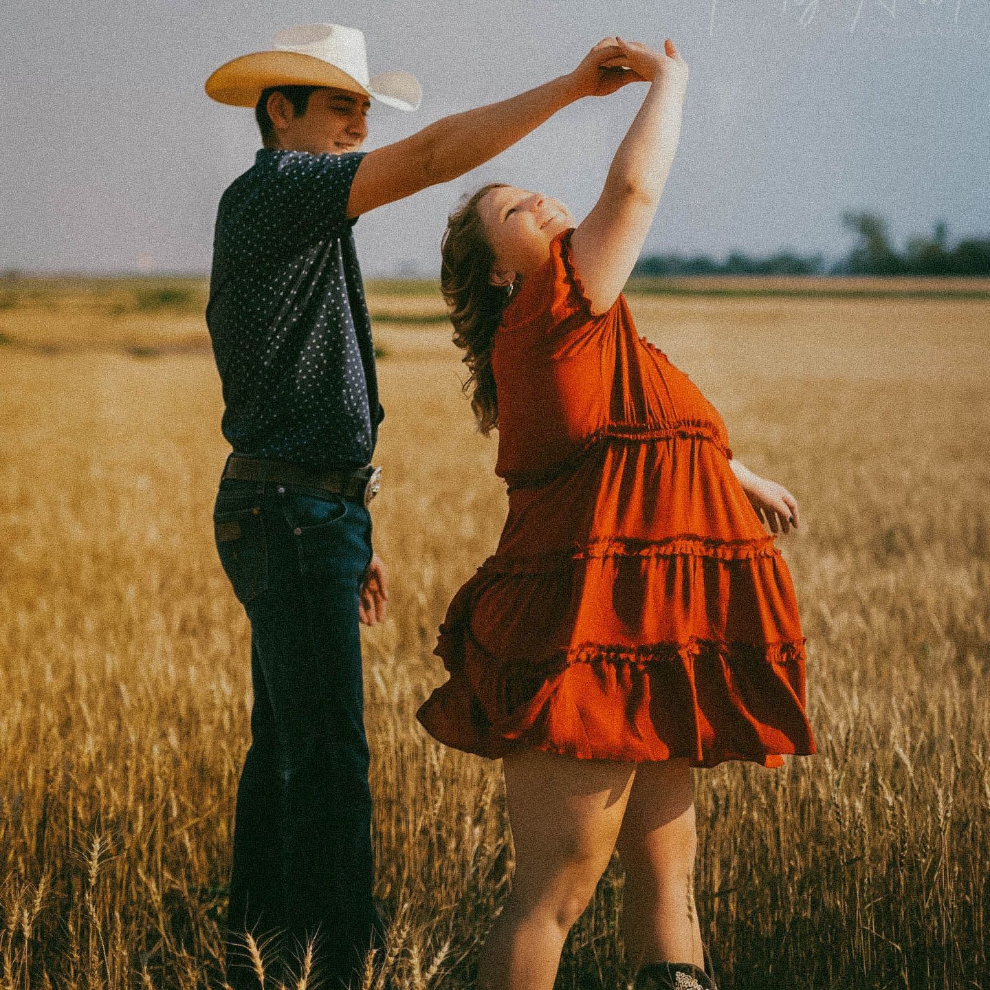 Western-style couple posing on a vintage truck for couple's portraits