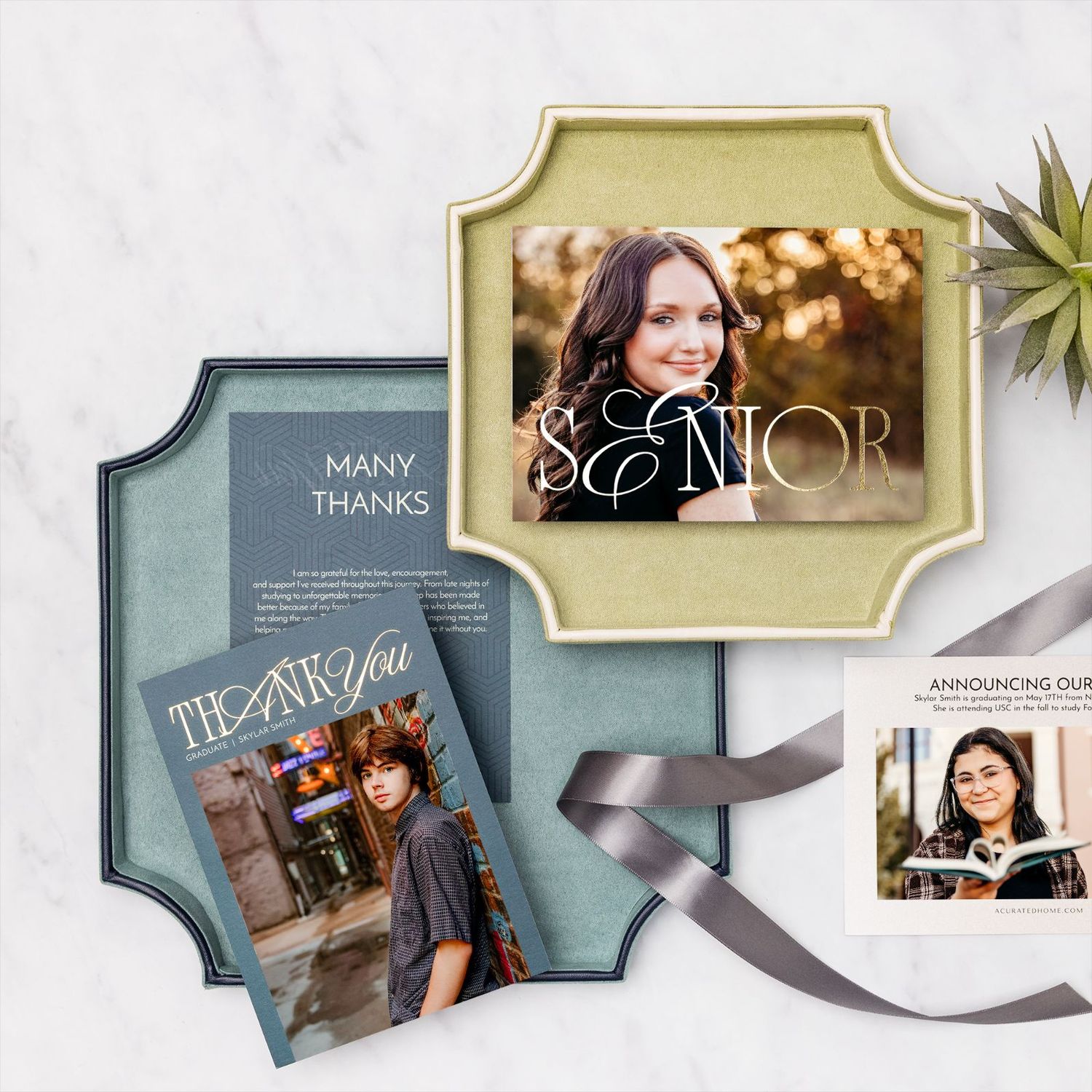 Senior graduation announcement cards and thank you notes displayed on a marble surface with ribbon accents.