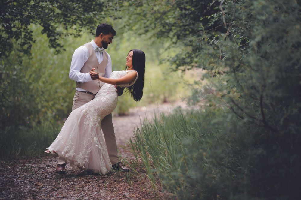 Couple sharing a romantic dance on a nature path surrounded by lush green trees.