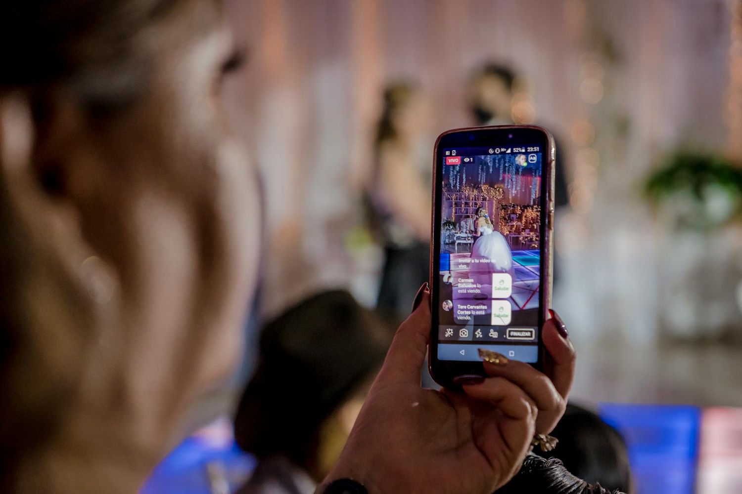 Someone holds a smartphone displaying a colorful social media app interface in low light conditions. looking for wedding videographers.