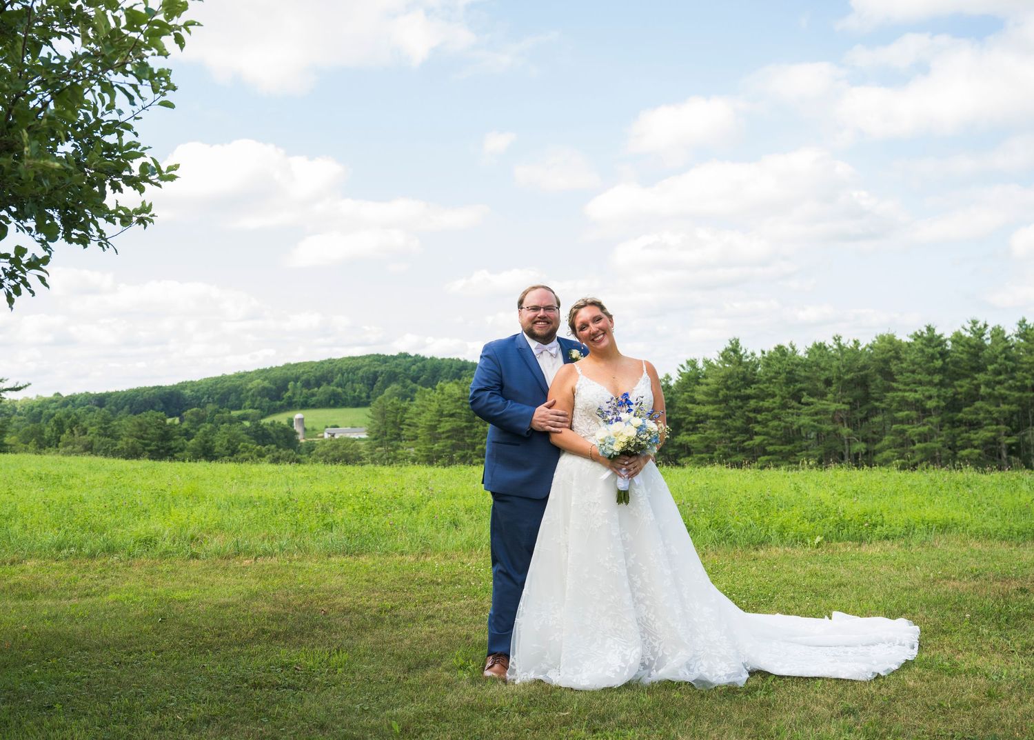 Newlyweds share an intimate moment outdoors with autumn foliage and rustic architecture in background.