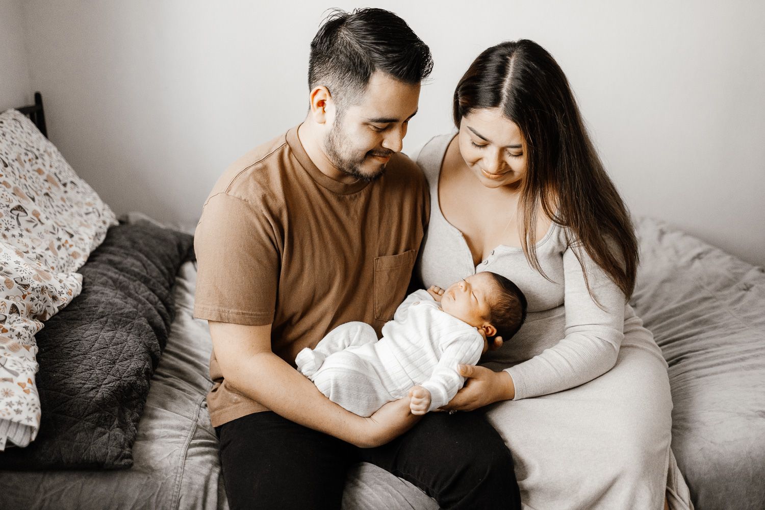 Parents look lovingly at their newborn baby at their Bay Area in-home lifestyle newborn photoshoot