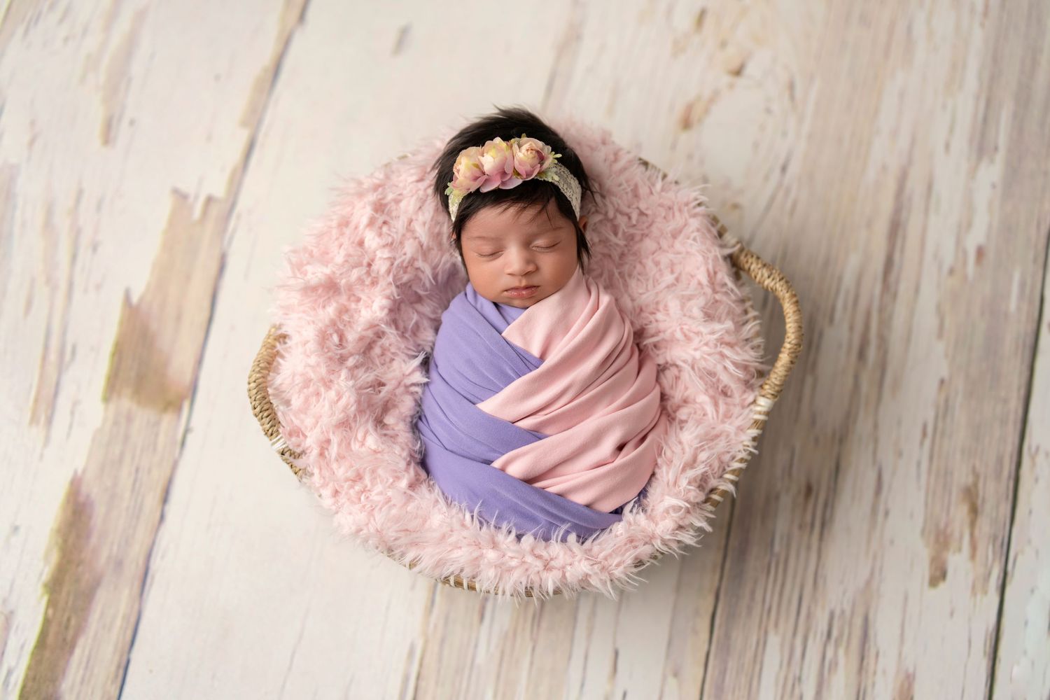 baby girl artistically wrapped in lavender and soft pink wrap with a lacy floral headband