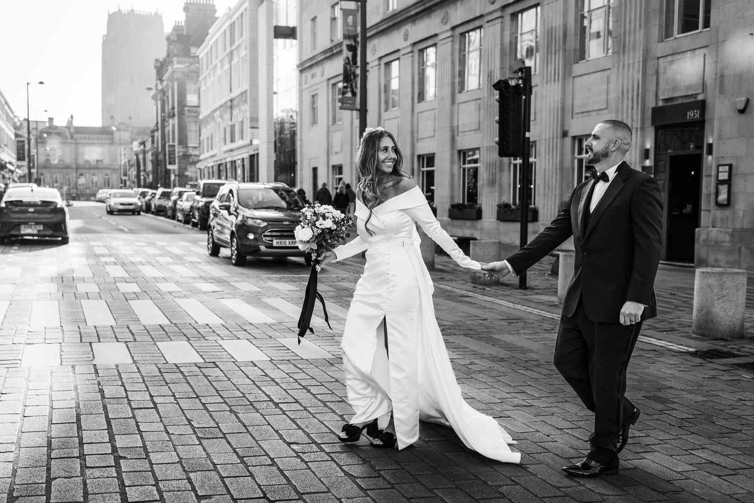 A bride and groom cross the road holding hands, Hope Street, Liverpool