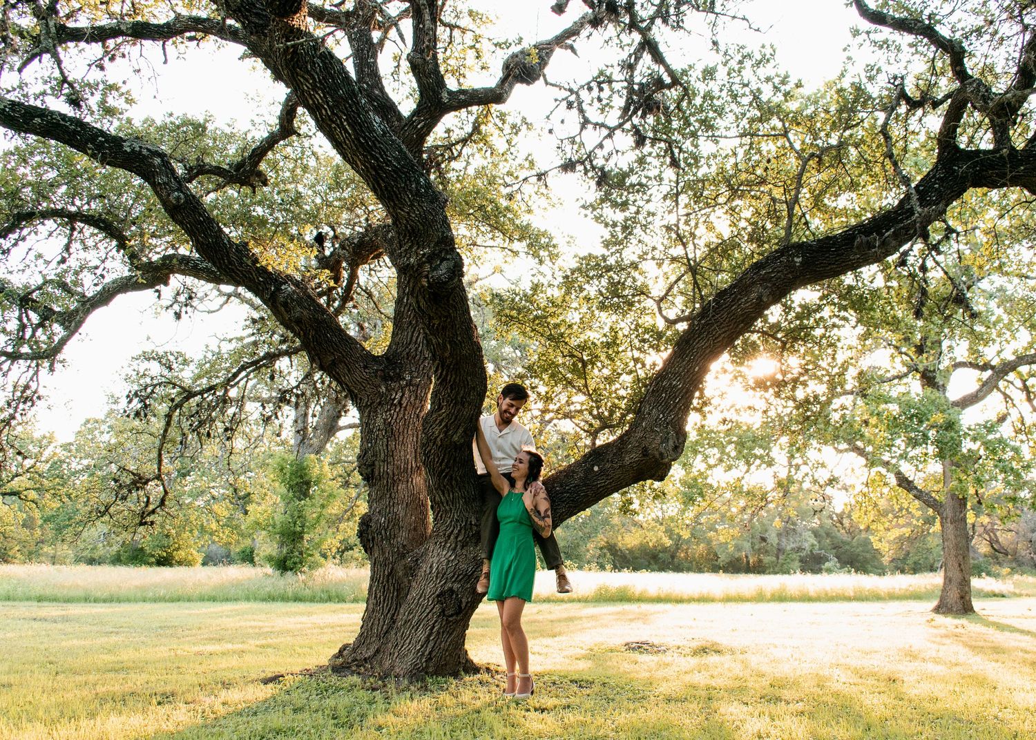 Engaged couple standing by oak tree during session at Circle C Park in Austin Texas