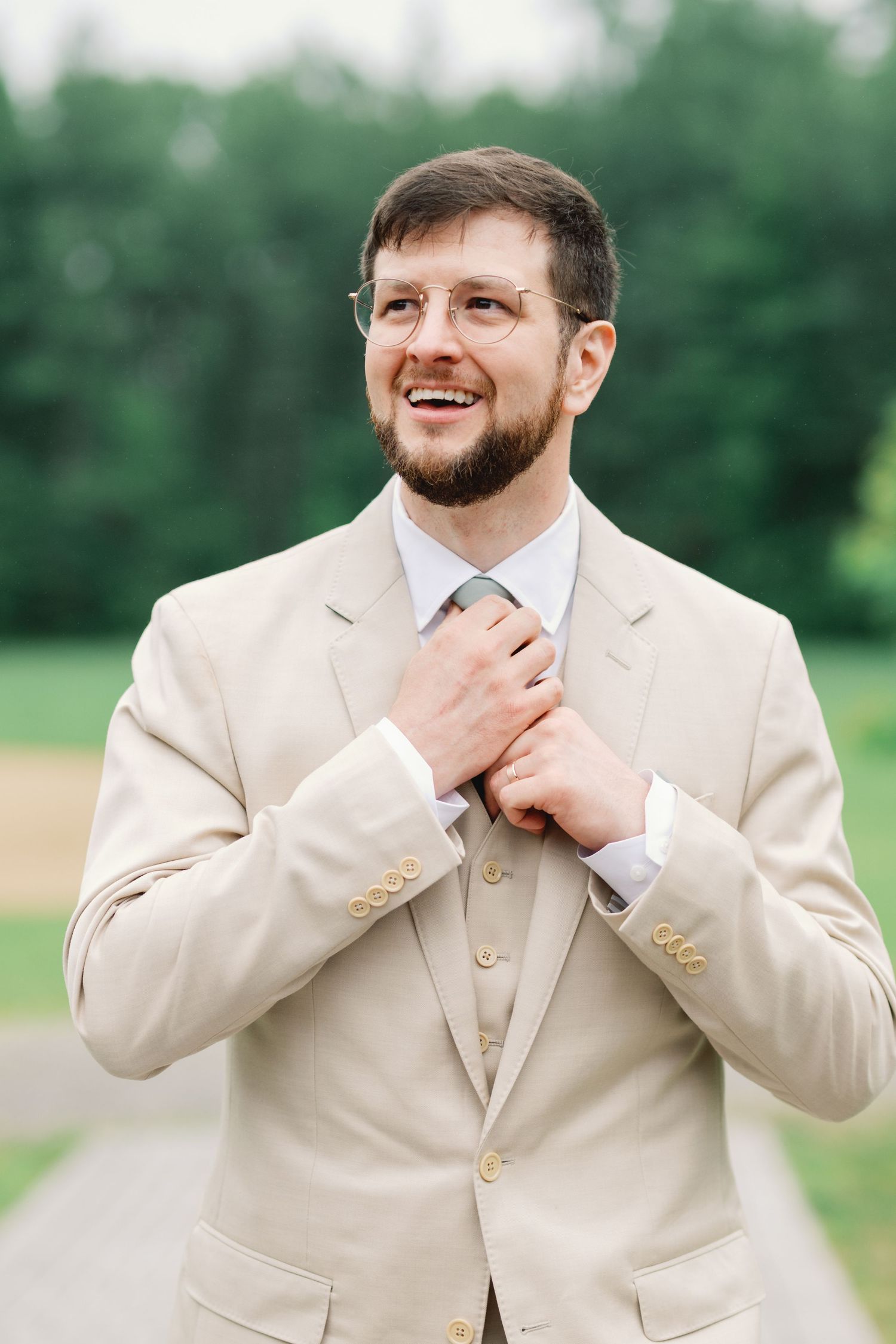 Black and white portrait of a groom in a tuxedo with boutonniere looking to the side in dramatic lighting.
