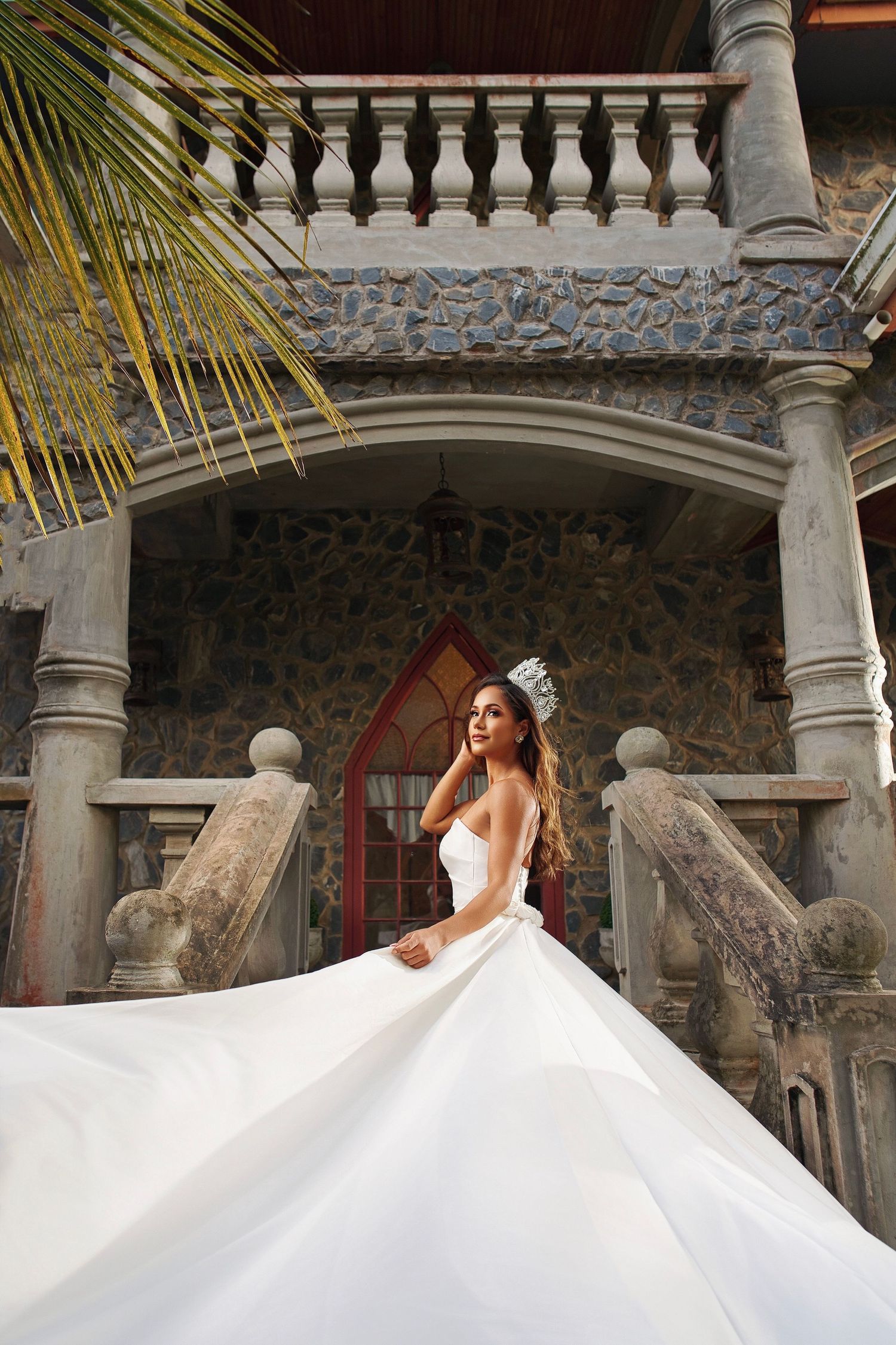 A flowing white wedding dress twirls gracefully against a stone balustrade and columns in an elegant outdoor setting.