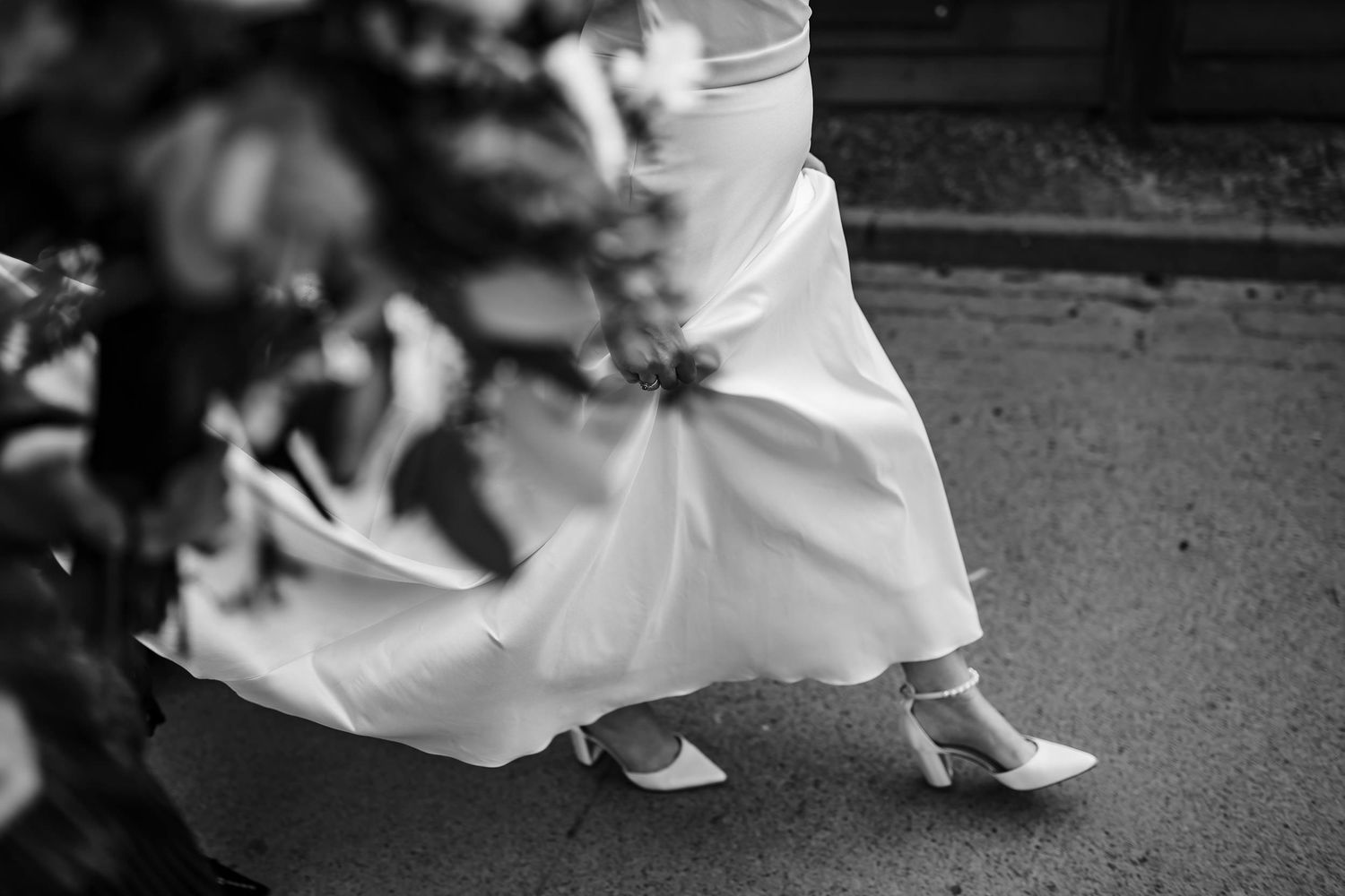 A black and white photo of legs and feet of people dancing in formal attire on a dance floor.