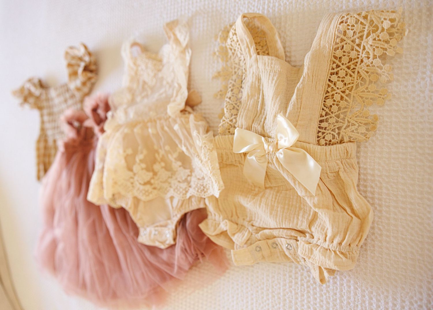 A horizontal collage of vintage lace garments and fabric details in soft cream and dusty pink tones.